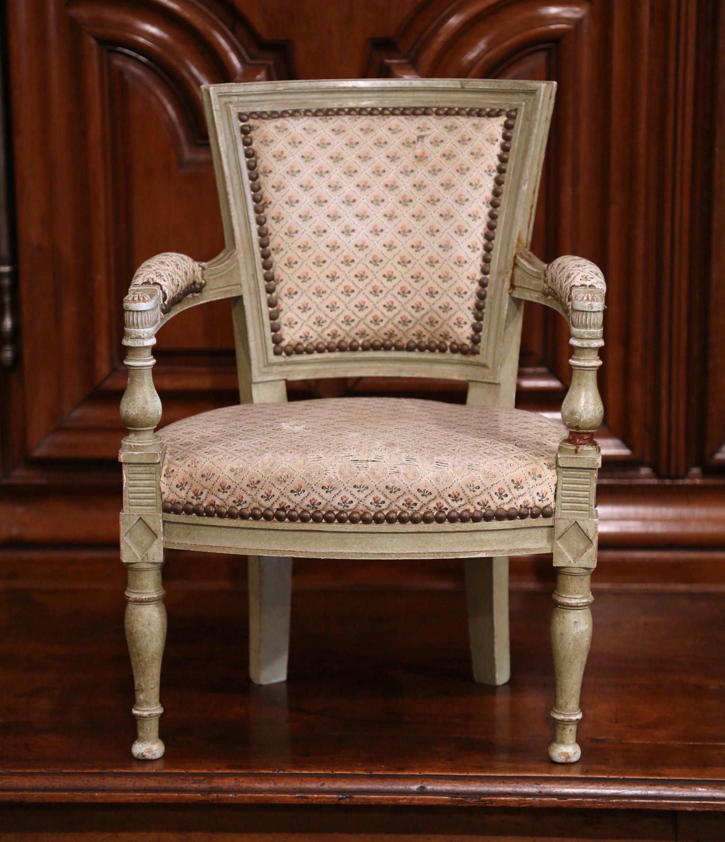 Ajoutez du charme à un salon familial ou à une chambre d'enfant avec cet élégant fauteuil pour enfants. Fabriquée en France vers 1860, cette chaise ancienne peinte présente un dossier carré, deux accoudoirs sculptés avec des médaillons floraux, et