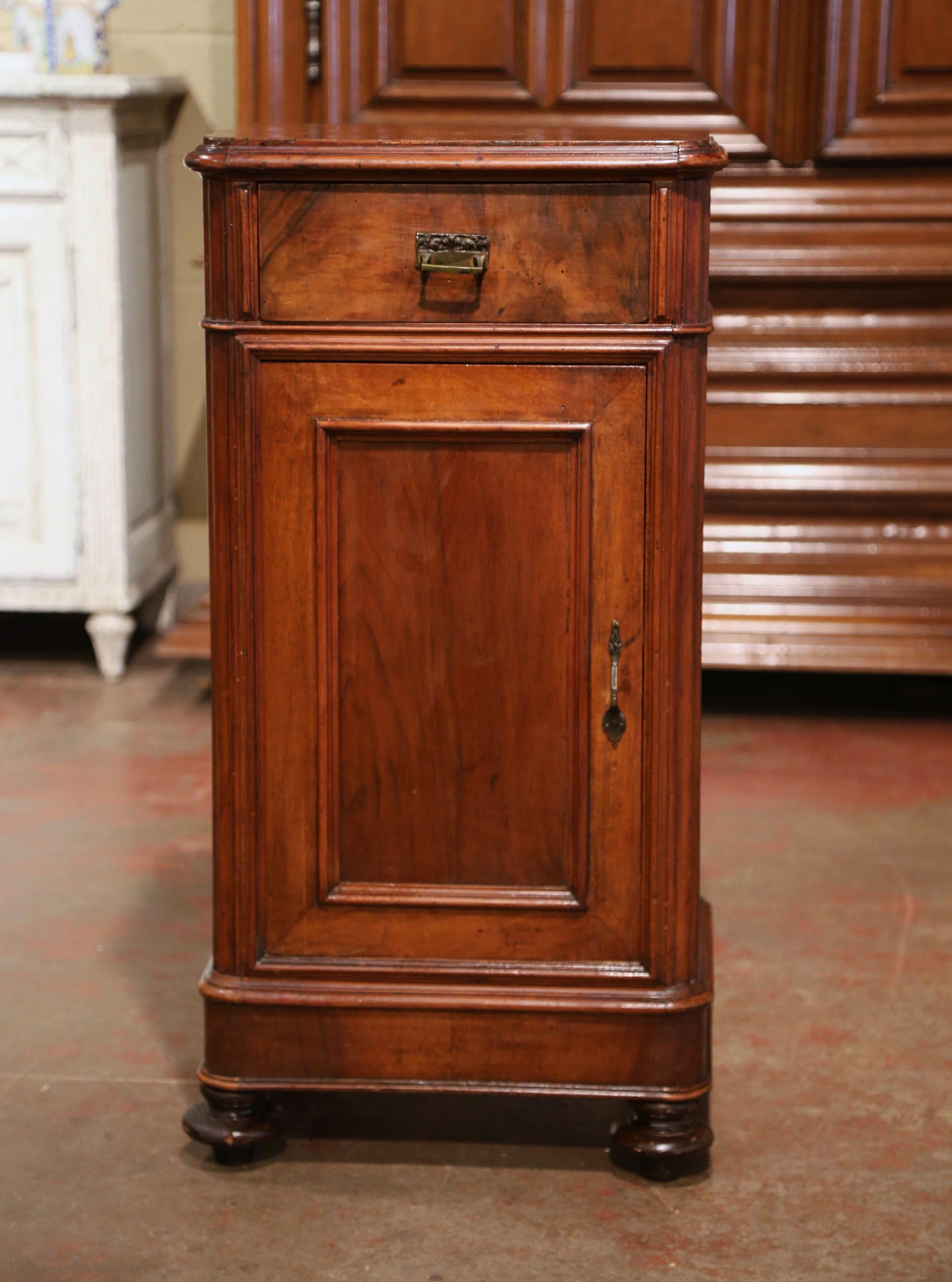This elegant antique nightstand was crafted in France, circa 1870. The fruit wood cabinet stands on front turned feet over a straight plinth; it features a single drawer over a large door with recessed panel, and decorated with spline fluted