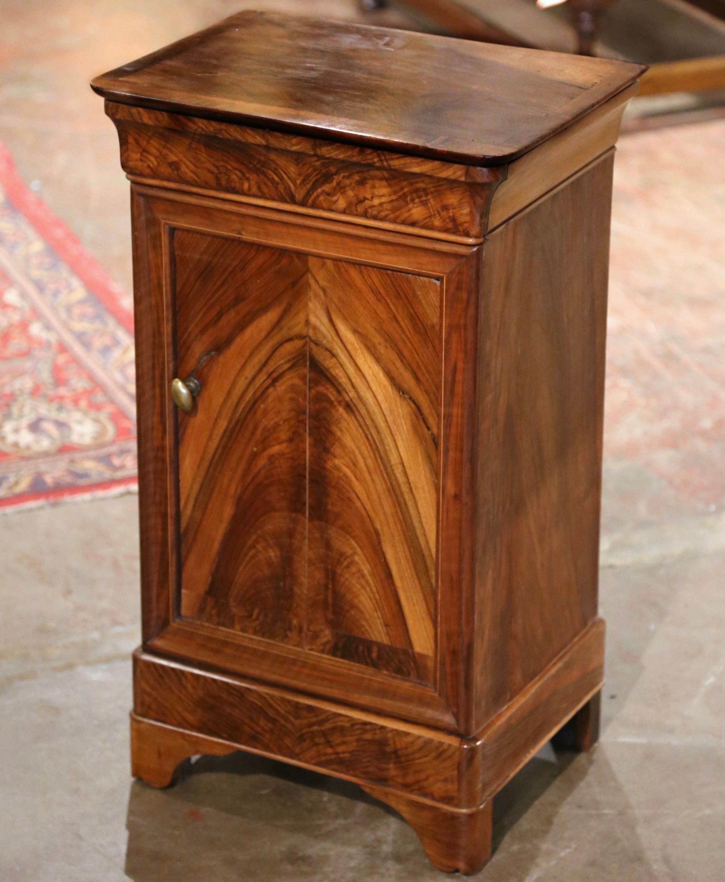 This elegant antique nightstand was crafted in France, circa 1890. The fruit wood cabinet stands on bracket feet over a straight plinth; it features a single frieze drawer over a large door decorated with recessed panel; the door is dressed with a