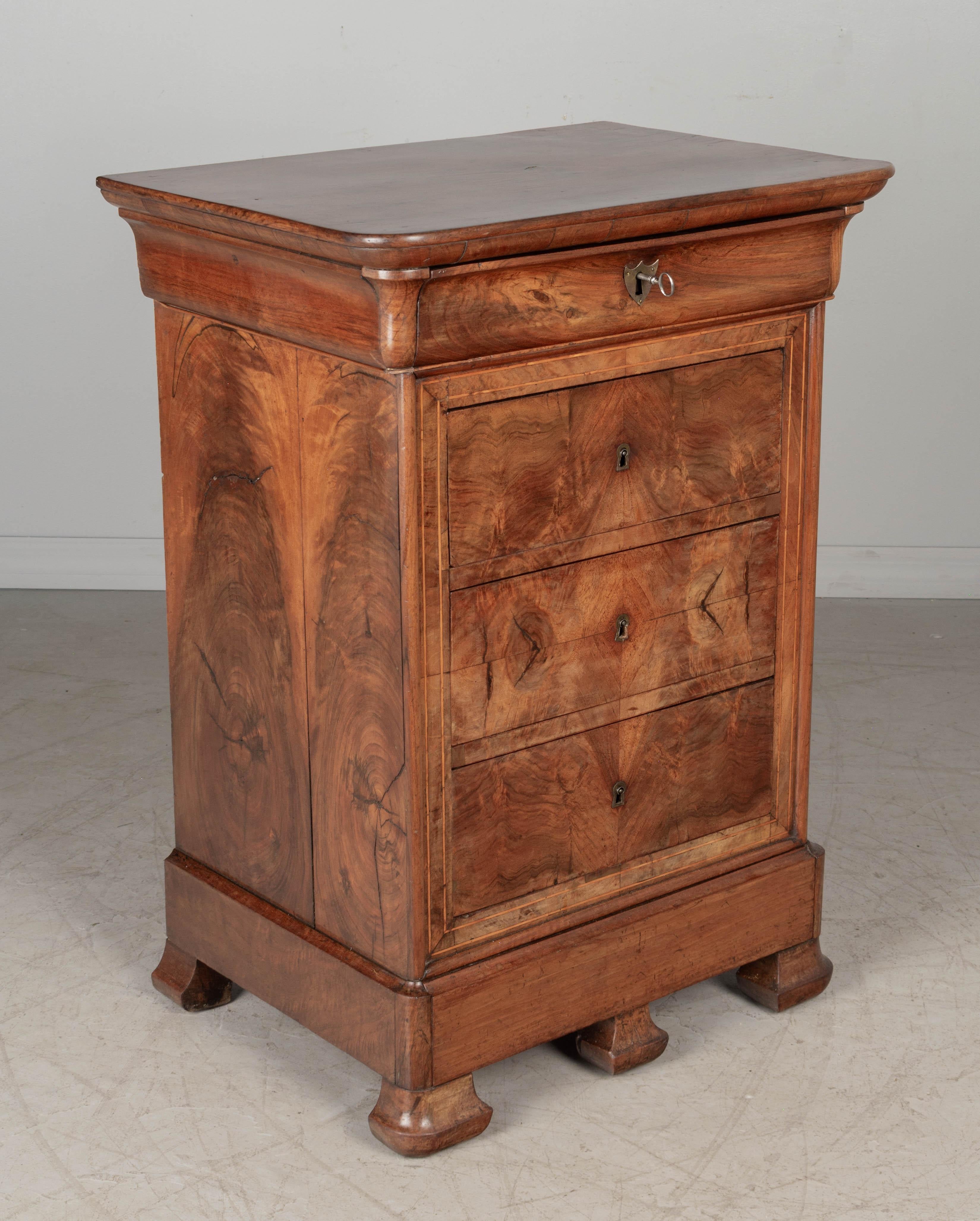 An early 19th century French Louis Philippe small commode, or stand, made of solid walnut with book-matched veneer of walnut. Four dovetailed drawers with working locks and one key and a bottom pullout with concealed compartment. Beautiful patterned