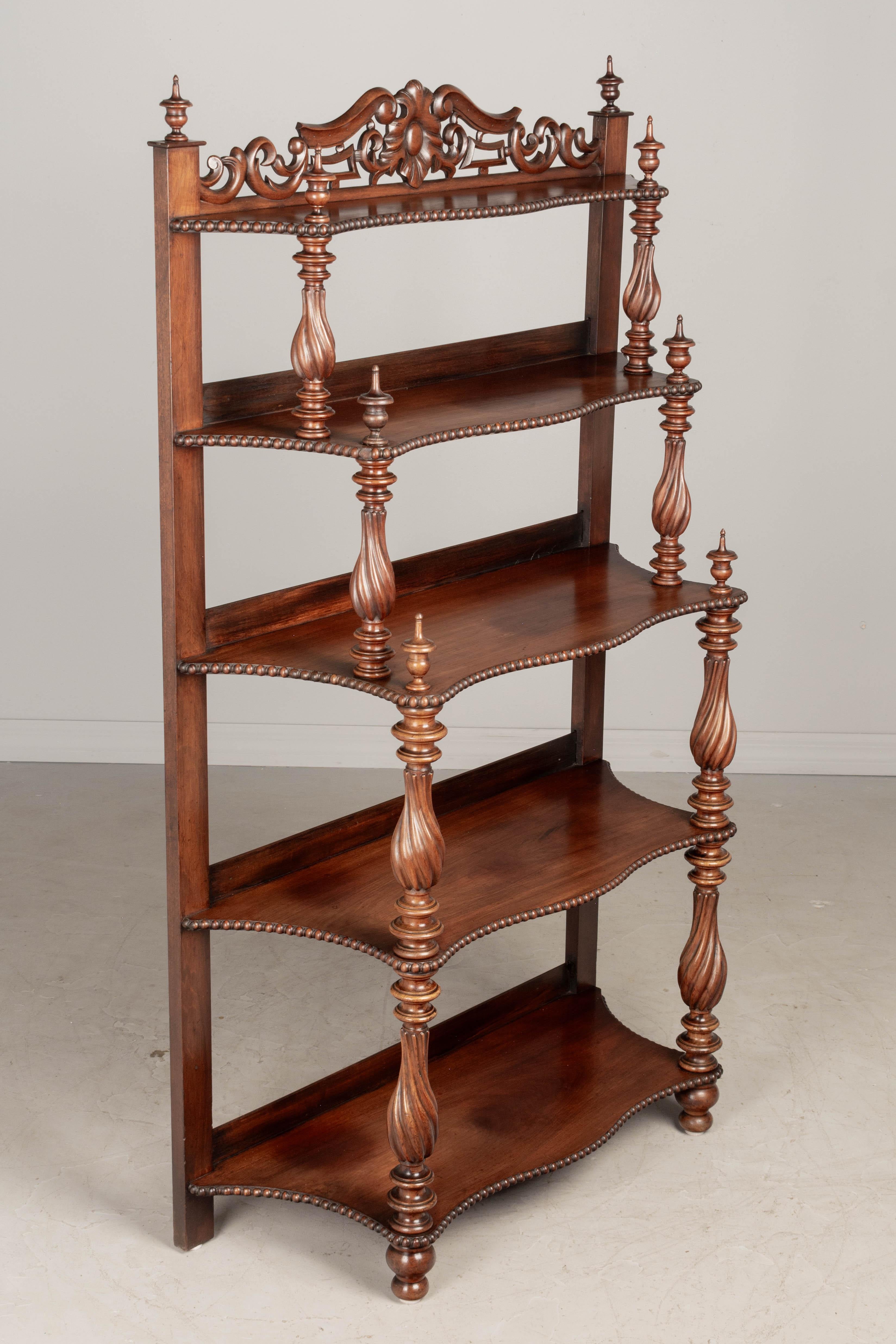 A 19th century French Louis Philippe étagère, or tiered shelf, made of solid mahogany, finished on all sides and retaining a nice luster. Shaped shelves with bead trim supported by turned columns with finials. Decorative carved crown. Fine turning.
