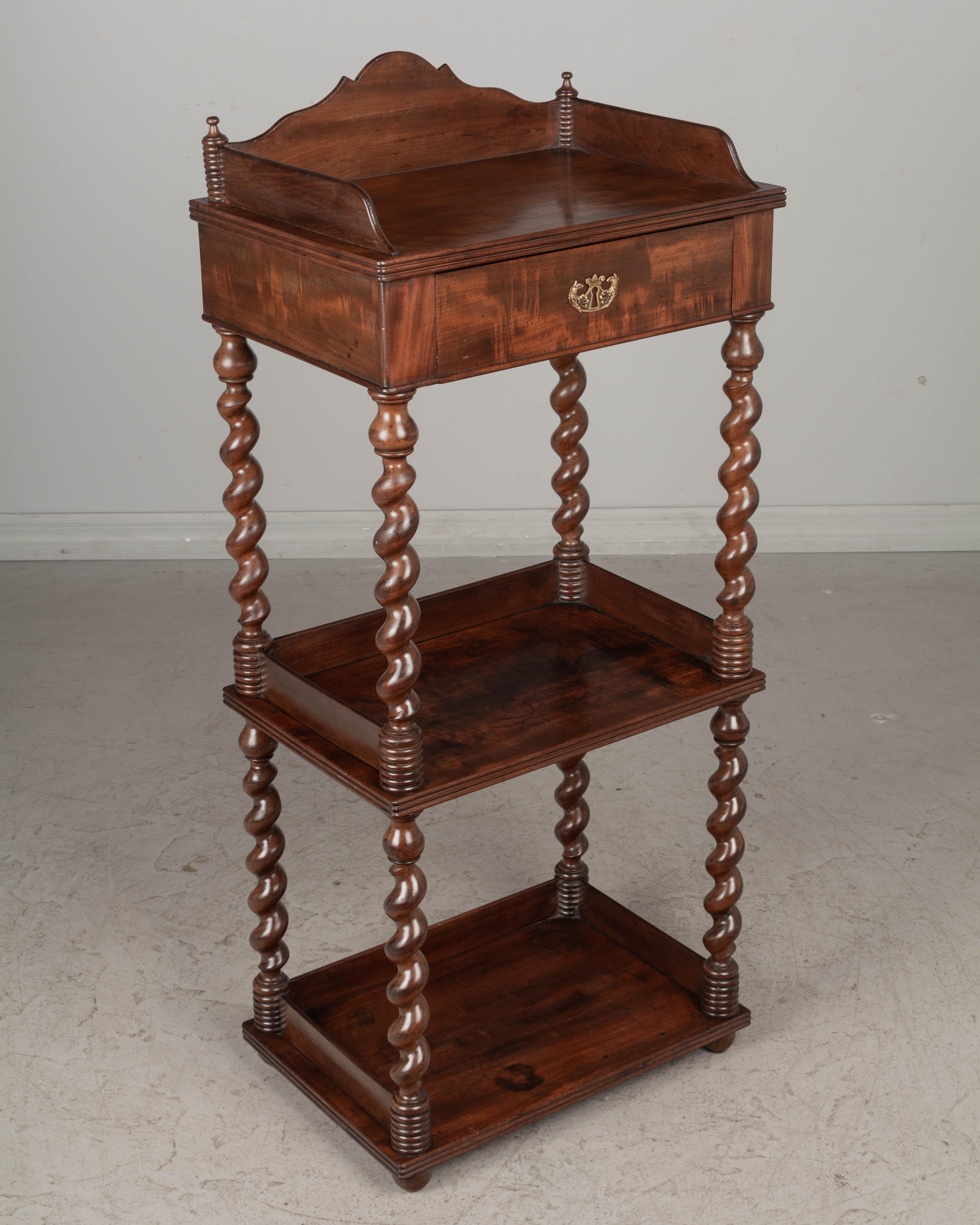 A 19th century French Louis Philippe étagère, or tiered stand, made of solid mahogany, finished on all sides and retaining a nice luster. Turned barley twist columns support the shelves Dovetail drawer at the top with flame mahogany veneer and
