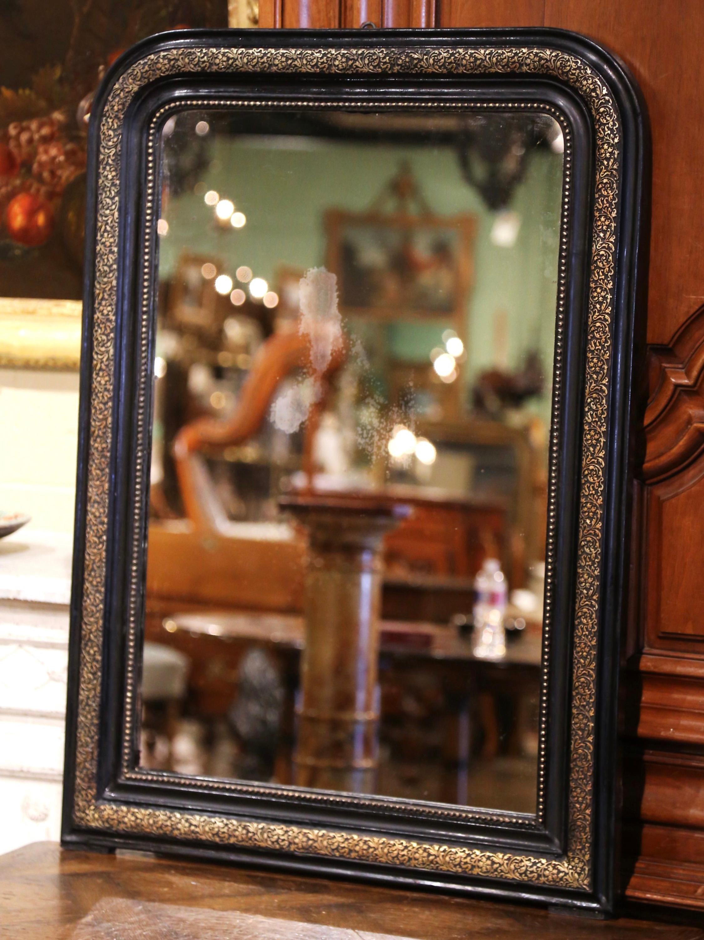 This elegant antique mirror with gold leaf and black lacquered was crafted in Southern France, circa 1860. The frame is decorated with hand carved repousse foliage motifs further embellished with bead decor around the frame. The wall hanging piece