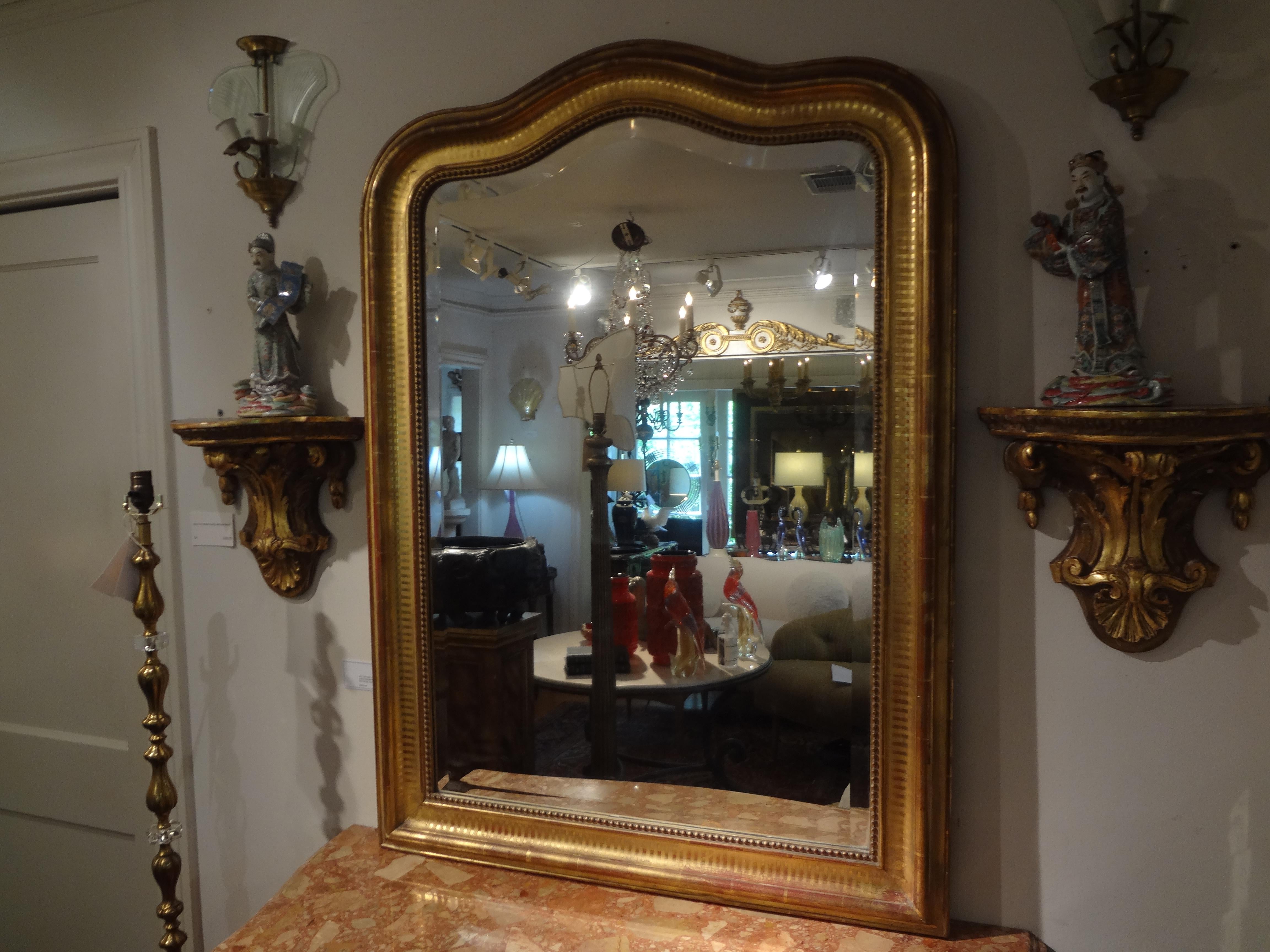 Stunning 19th century French Louis Philippe giltwood beveled mirror. This shapely antique Venetian mirror has a beautifully decorated engraved design around the perimeter and would look great in an entrance hall, a powder room, above a console,