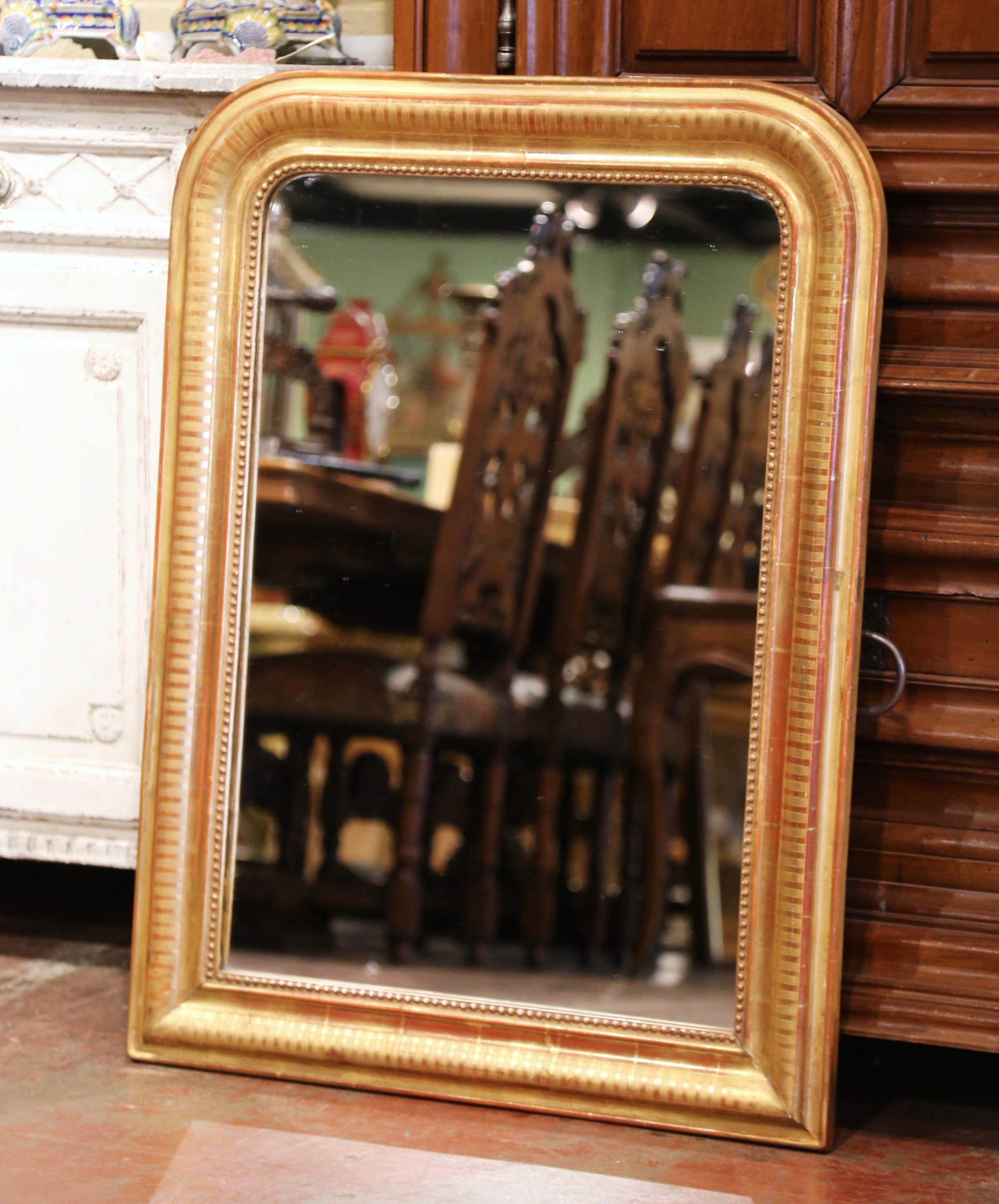 Crafted in the Burgundy region of France circa 1870, the antique mirror has traditional lines with rounded corners; the rectangular frame is decorated with a discrete engraved geometric motif, and further embellished with decorative beads around the