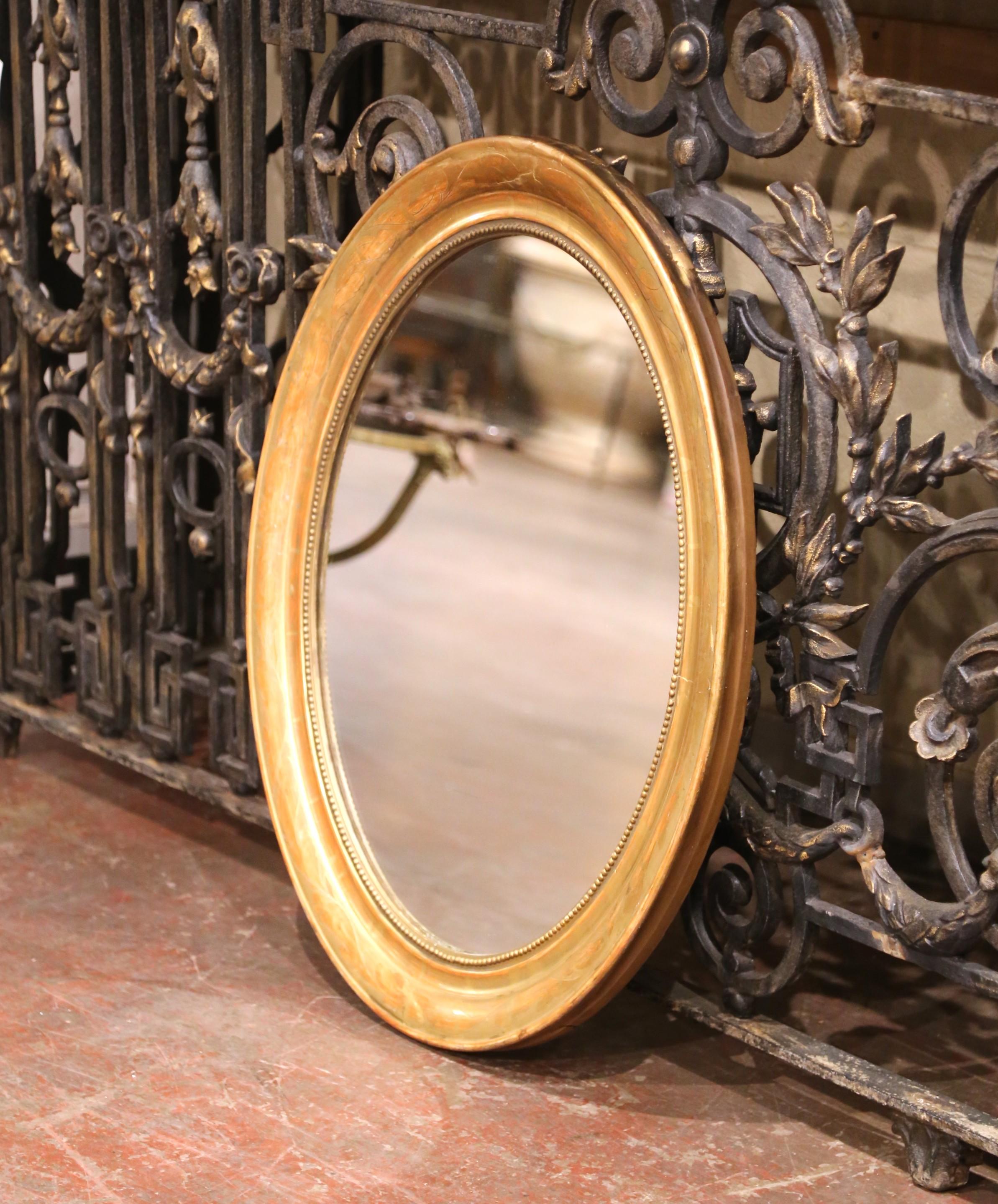 Decorate a powder room or entryway with this elegant antique wall mirror. Crafted in France, circa 1870, and oval in shape, the frame is decorated with an discrete engraved floral motifs and embellished with bead decor. The Louis Philippe style
