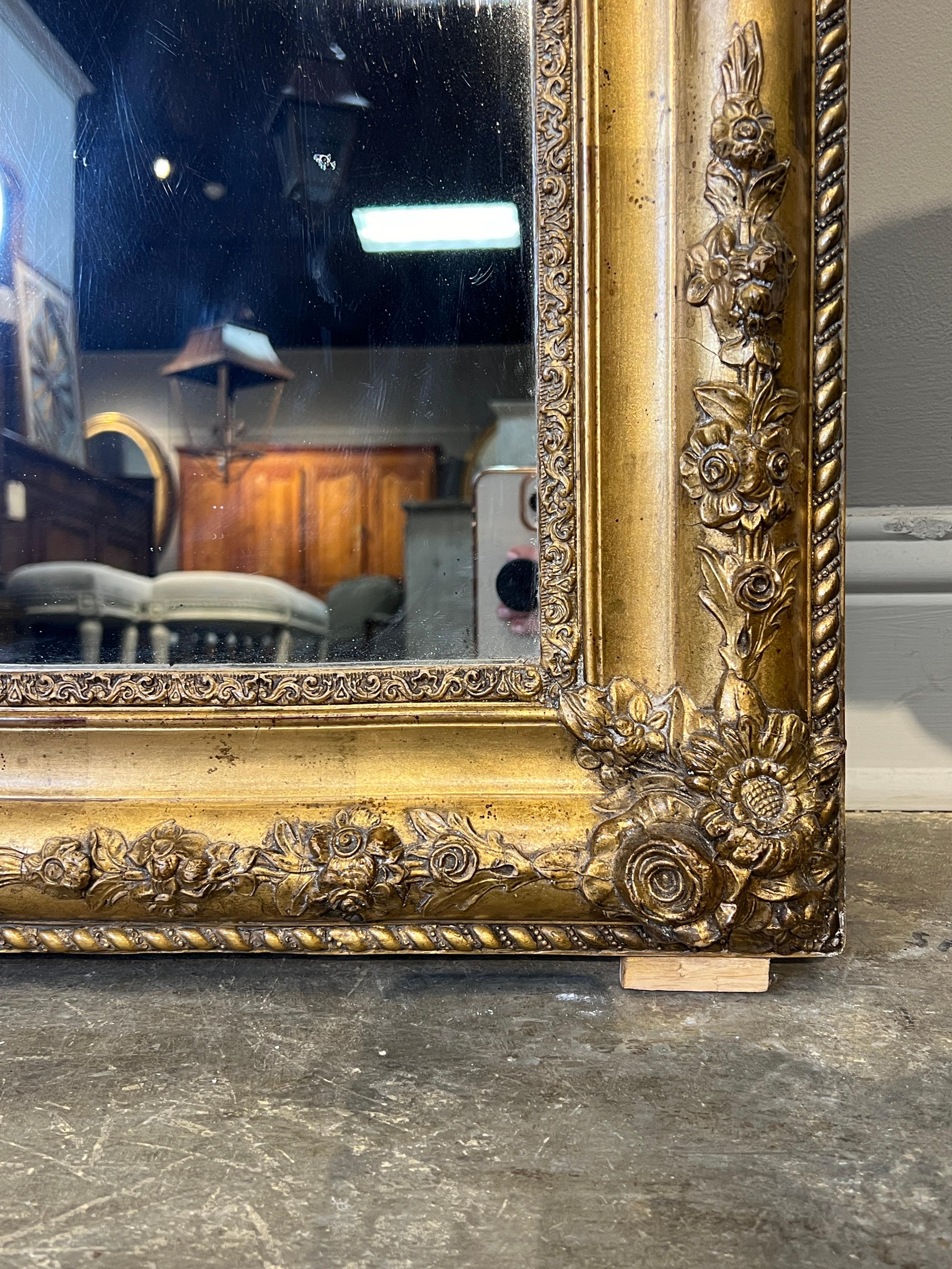 A lovely 19th C. Louis Philippe style mirror with decorative elements of transition to third Empire style. Corners and rounded top of molded frame are decorated with flourishes of flowers. The inside border of the molded giltwood frame is in a