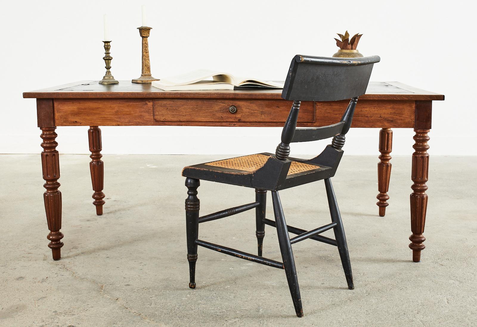 Rustic 19th century French Louis Philippe writing table or desk featuring a painted or waxed canvas writing surface. The table is crafted from an oak top inset with a unique black painted canvas writing surface and supported by a fruitwood case