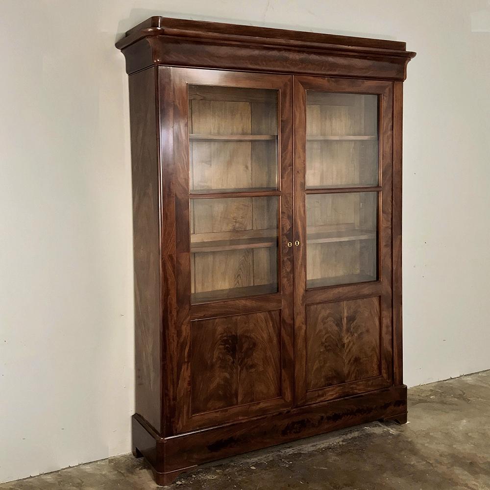 19th century French Louis Philippe mahogany bookcase makes the perfect choice for today's tailored decors! Handcrafted from exotic imported mahogany, it features a generous glazed upper portion with panels below formed by bookmatched flame mahogany