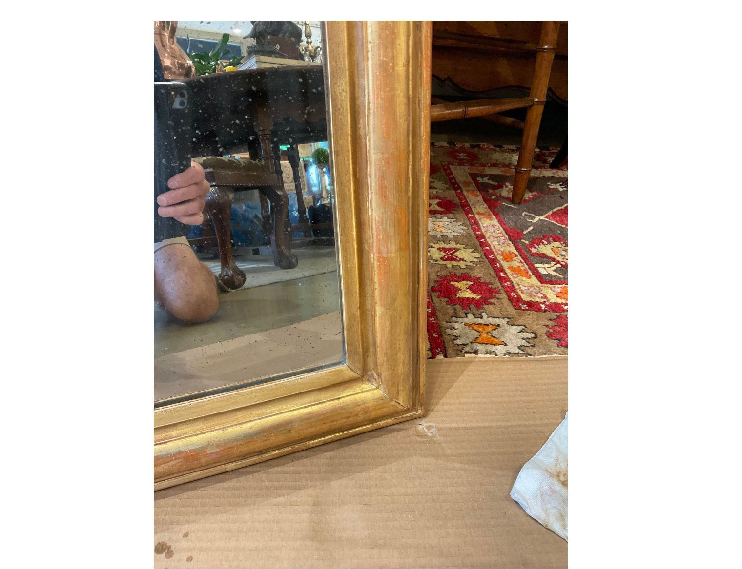 A stunning 19th century French Louis Philippe mirror. This mirror is all original including its glass. Its gold gilt goes all around and is worn away reveling the red under coat indicates its true age. A mirror like this makes such a statement and