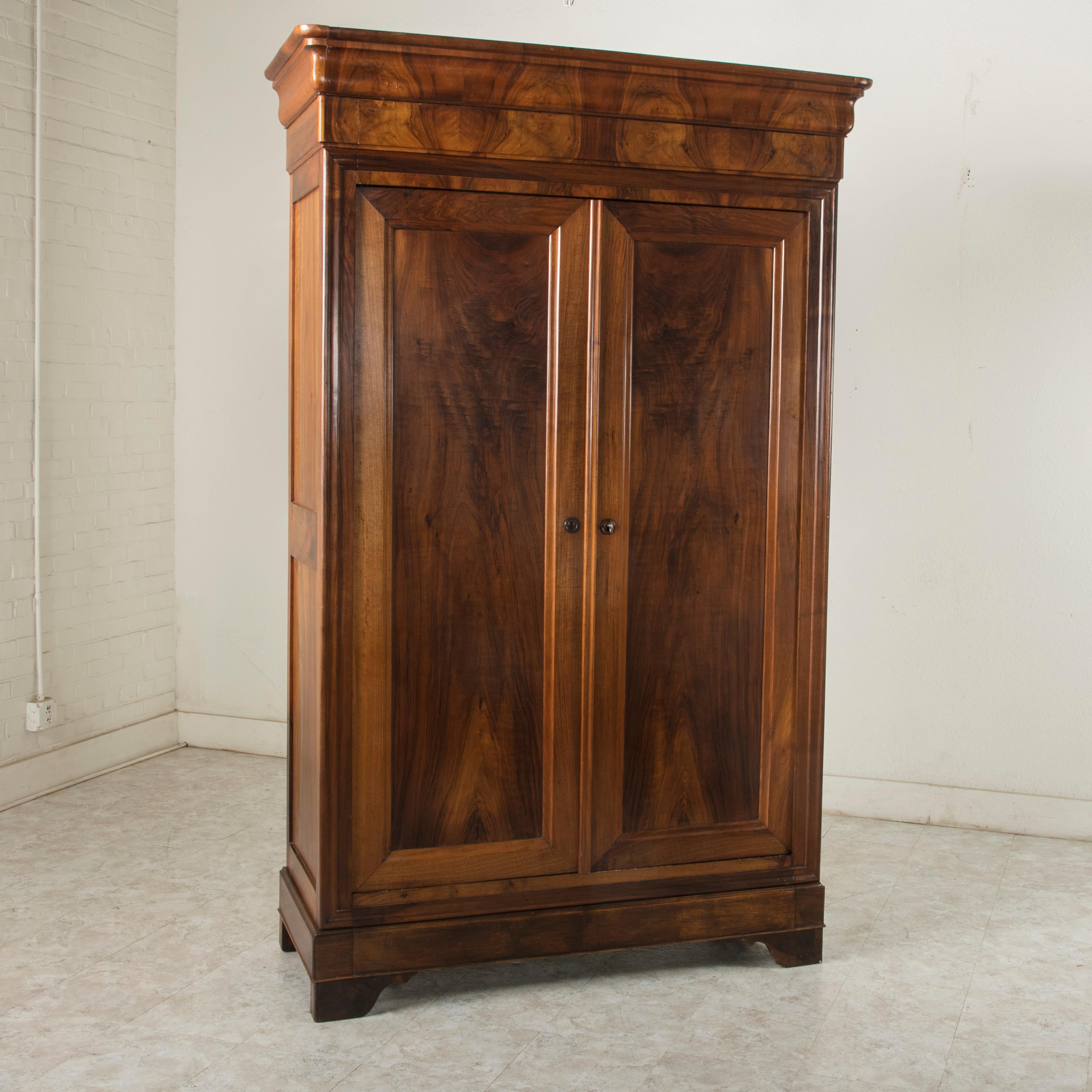 Found in Angers, a city in the Loire Valley castle region of France, this 19th century bookmatched walnut armoire features simple clean lines, the Classic distinction of the Louis Philippe style. A period piece, its solid paneled sides and doors
