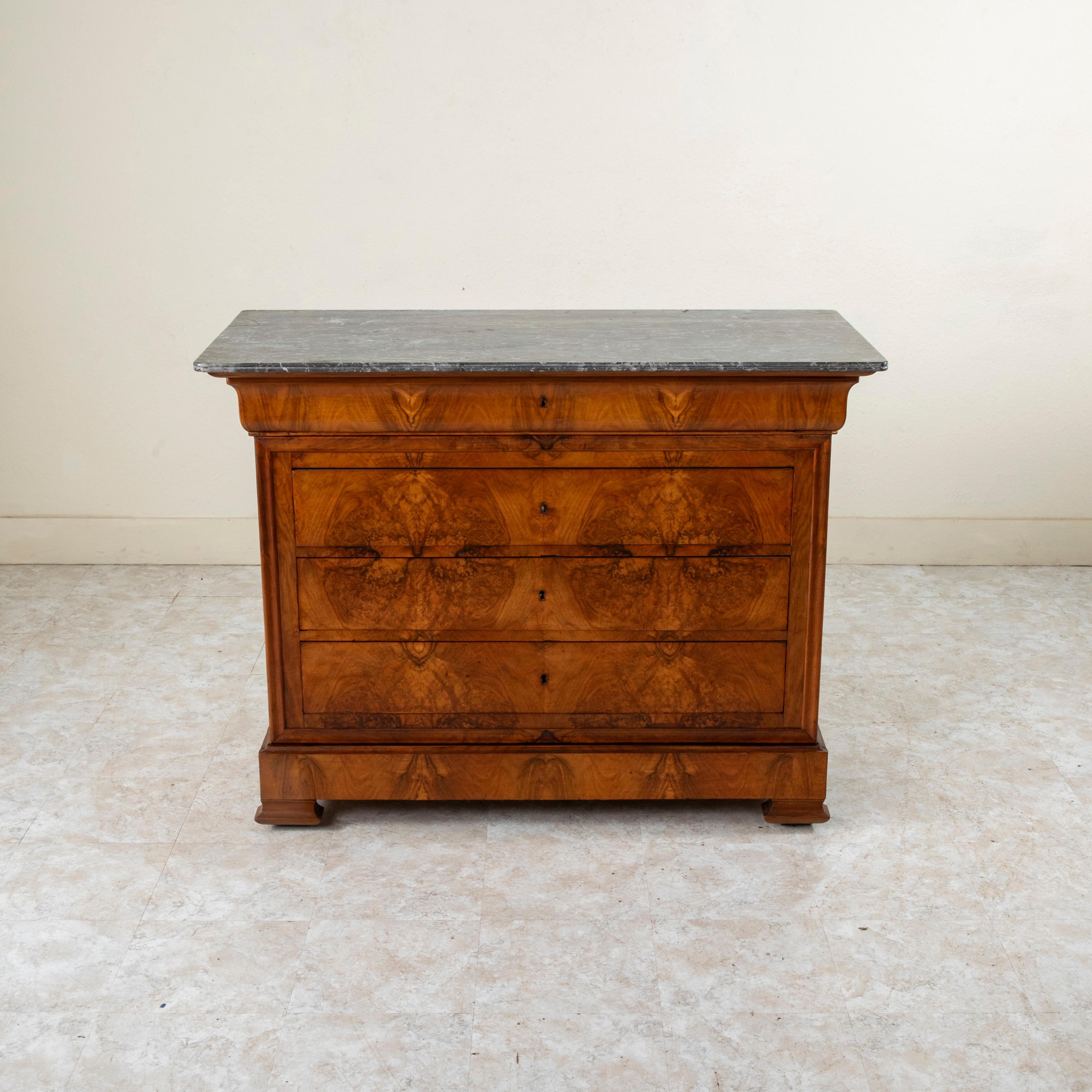 This quintessential Louis Philippe period commode or chest of drawers displays the exemplary craftsmanship of the early nineteenth century with a facade of book matched burl walnut and solid walnut panel sides. The piece is capped with a double