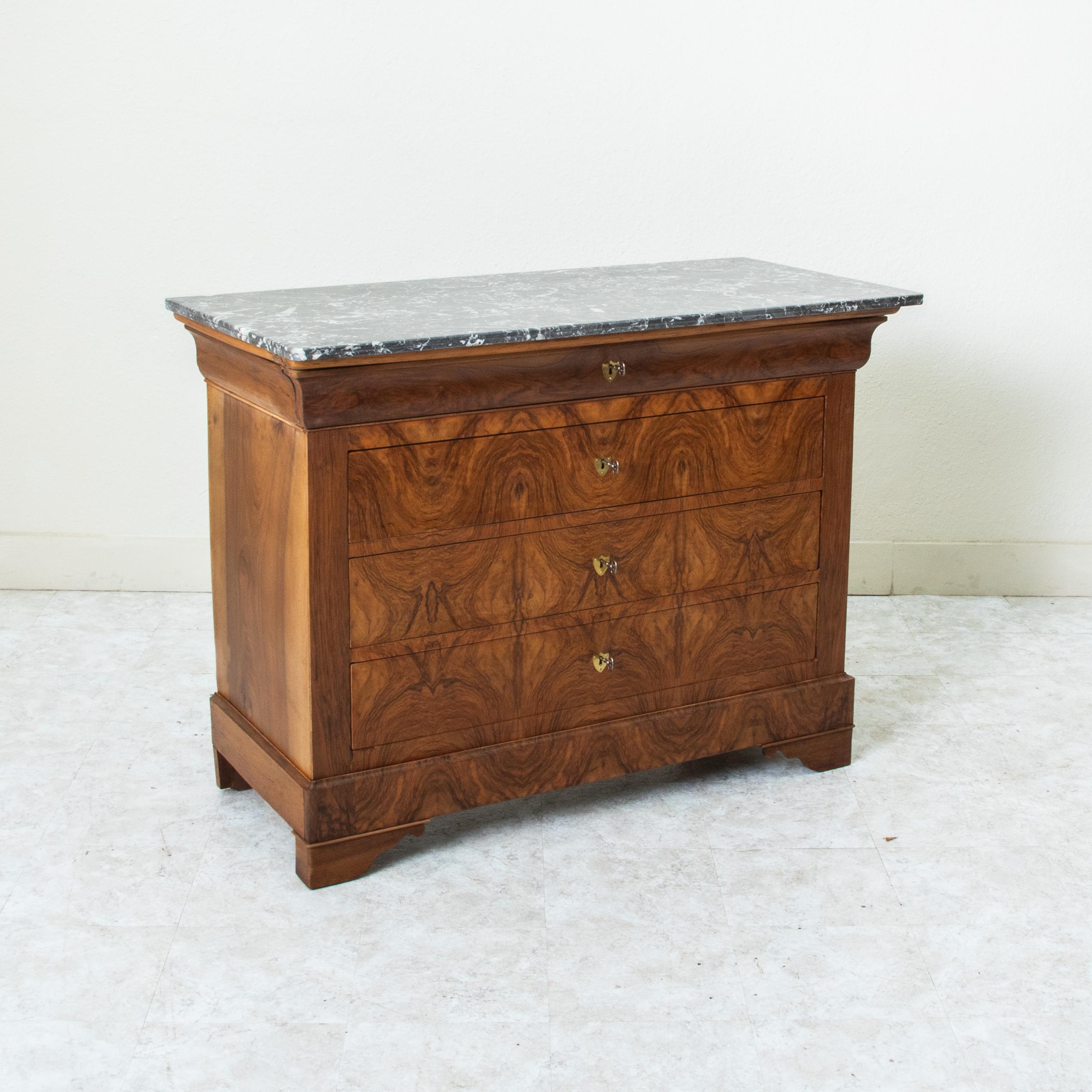 This quintessential Louis Philippe period commode or chest of drawers displays the exemplary craftsmanship of the early nineteenth century with a facade of book matched burl walnut and solid walnut panel sides. The piece is capped with a double