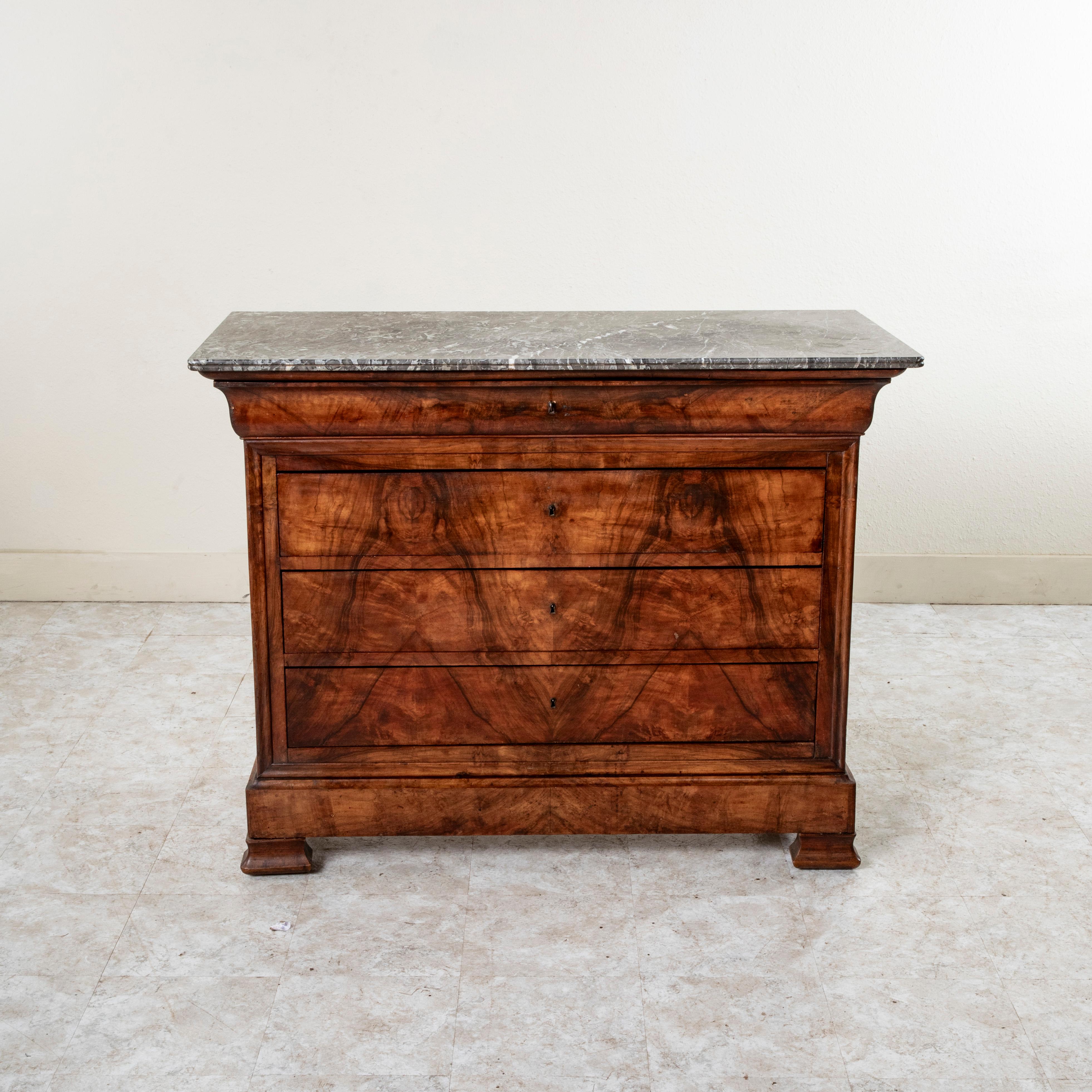 This quintessential Louis Philippe period commode or chest of drawers displays the exemplary craftsmanship of the early nineteenth century with a facade of book matched burl walnut and solid walnut panel sides. The piece is capped with a double