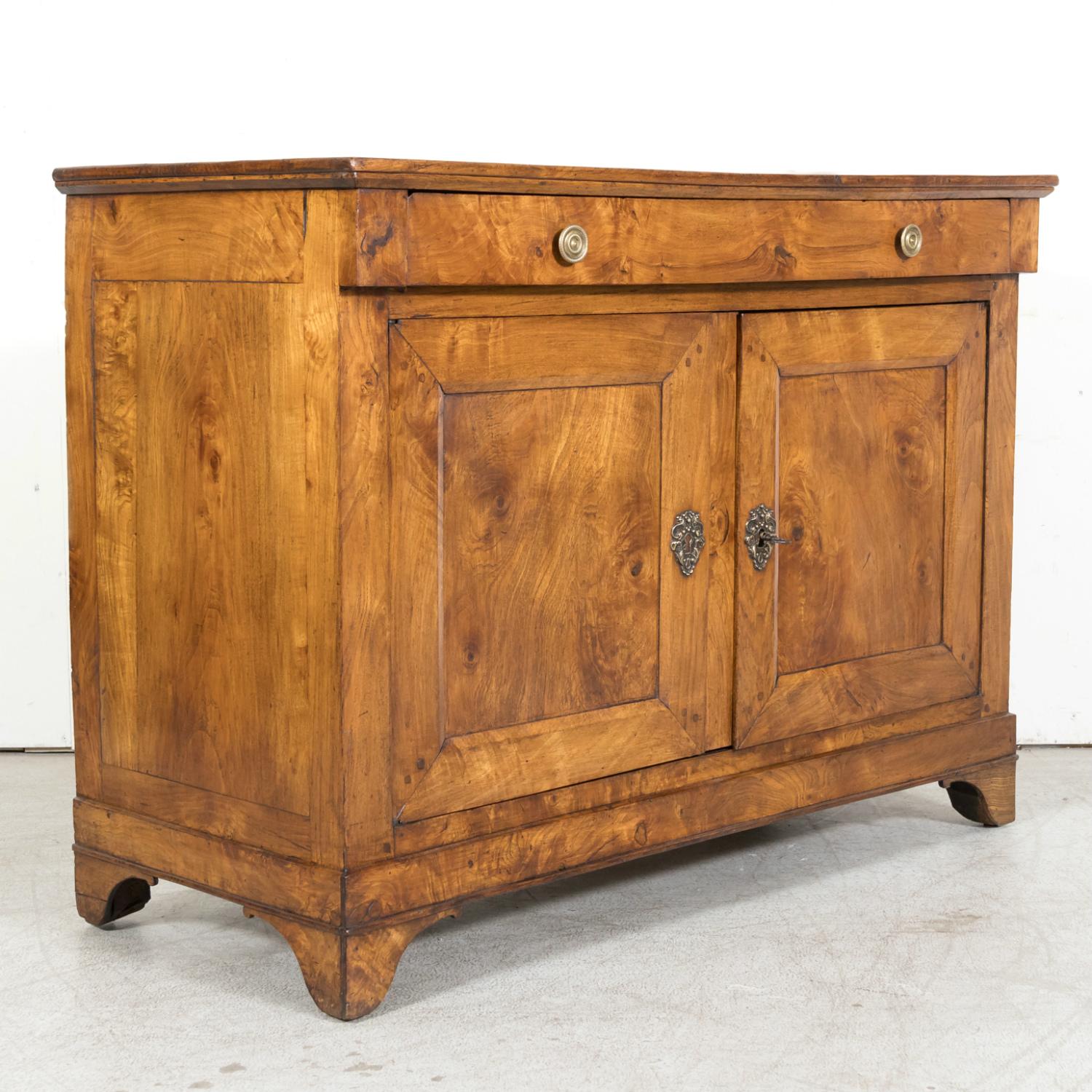 A 19th century French Louis Philippe period buffet handcrafted of burled chestnut in the South of France, circa 1840s, having a rectangular plank top sitting above two drawers with circular brass pulls over two doors that open to reveal a single