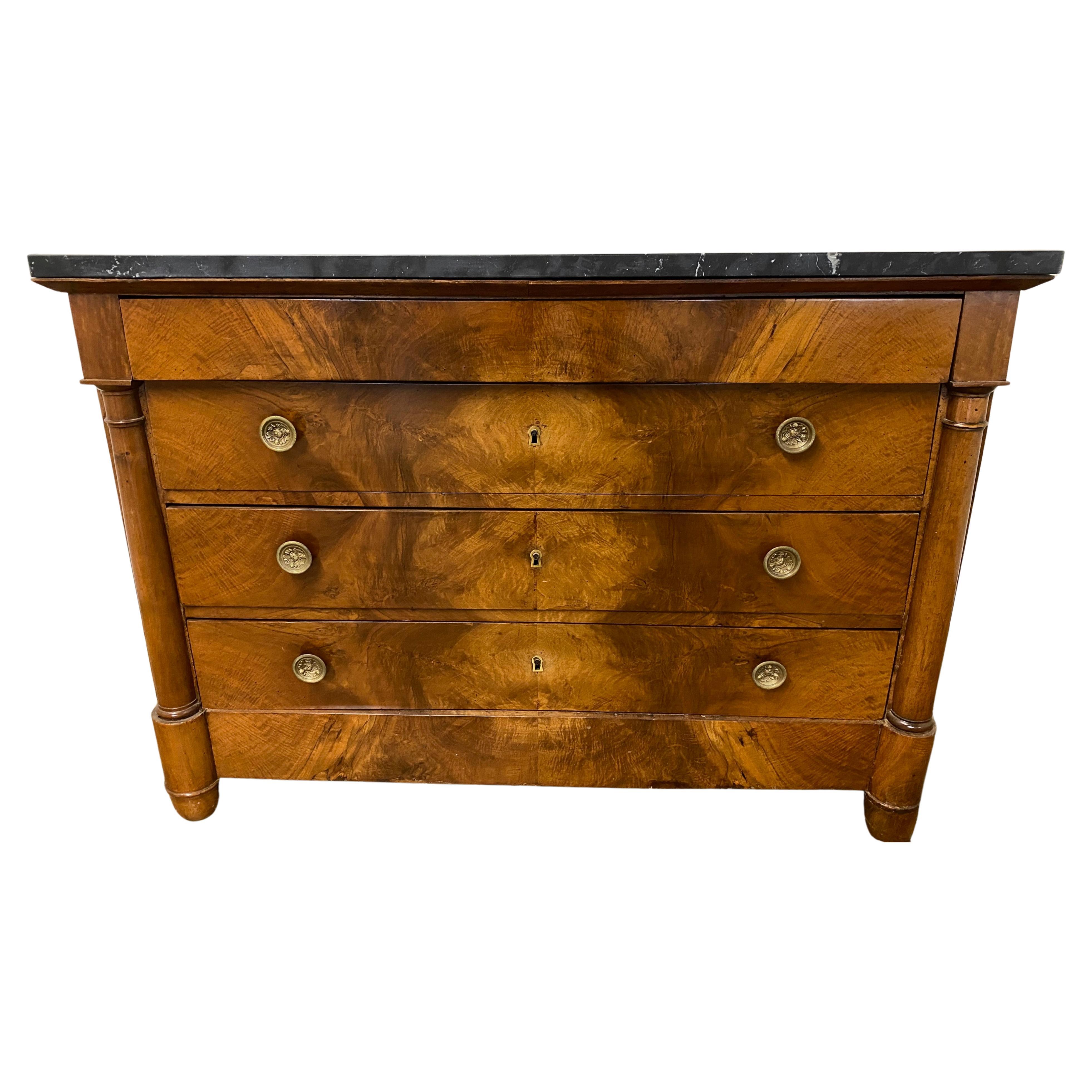 A fine example of early 19th Century French chest of drawers with black marble top, rounded columnar sides terminating on rounded block feet. This Empire period commode from the reign of Napoleon I, with exterior of book matched mahogany veneer