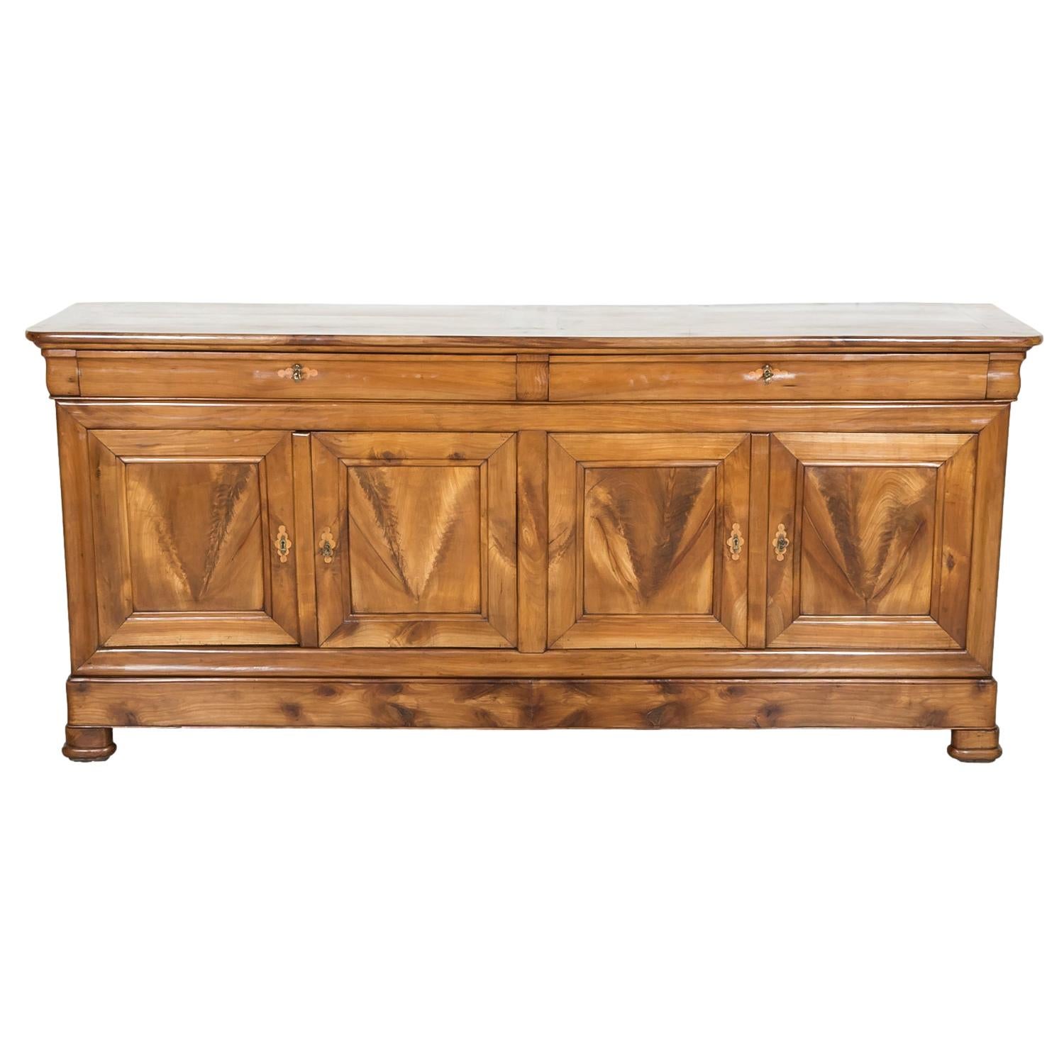 An impressive 19th century French Louis Philippe period enfilade buffet handcrafted by skilled artisans in the Brittany region of solid cherry wood with beautifully inlaid lemon wood escutcheons that only add to the authenticity and historical