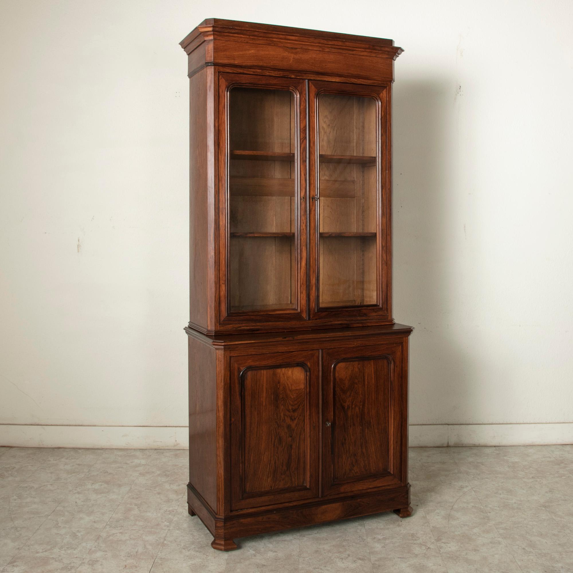 This 19th century French Louis Philippe period buffet deux corps or bookcase is constructed of palisander and features clean simple lines. Of an unusual size with its narrow width of 40 inches, its upper cabinet is fitted with glass doors and