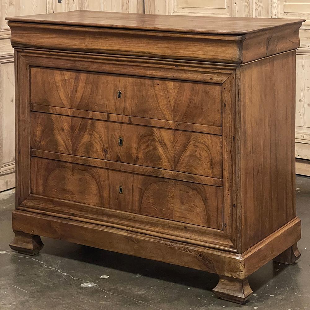 19th Century French Louis Philippe Period Walnut Commode is an intriguing example of the genre, hand-crafted from indigenous French walnut in the definitive style of the era, and adorned with bookmatched veneer across the drawer facade formed from