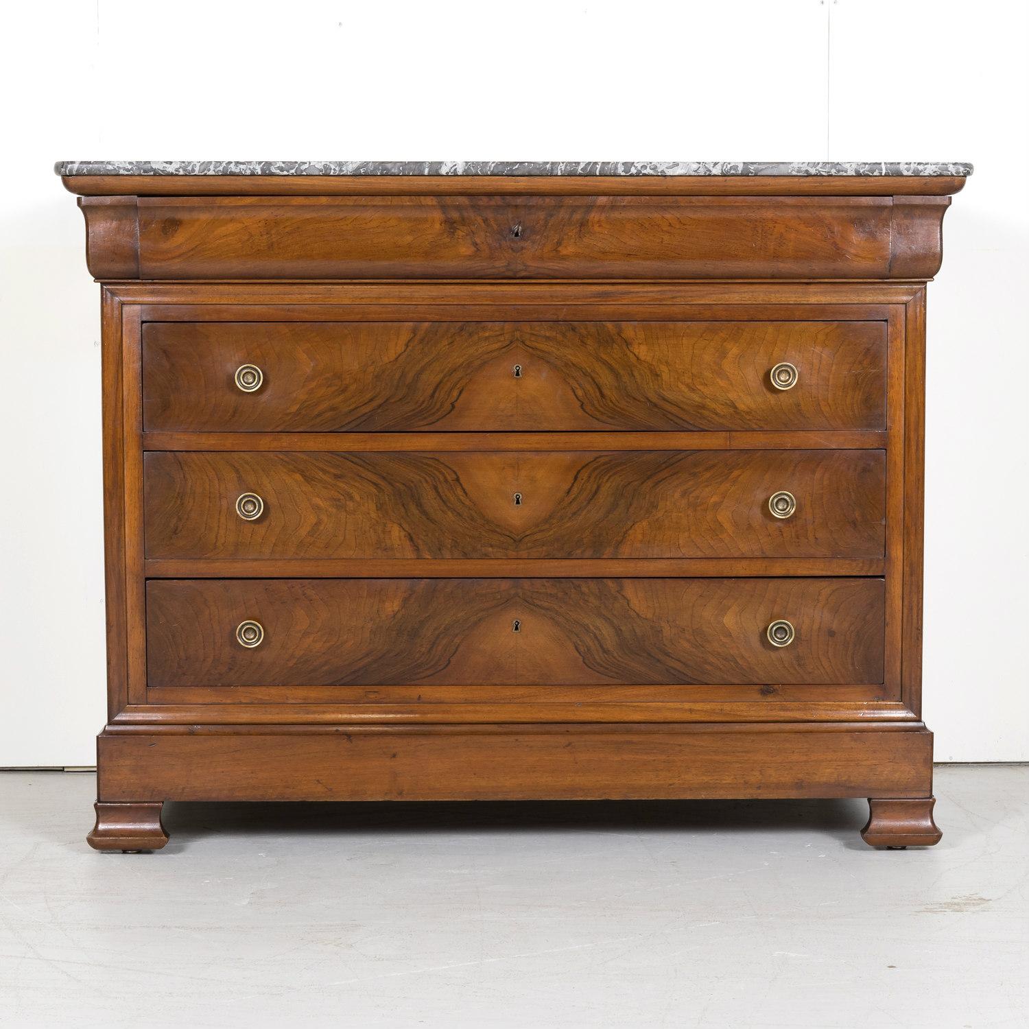 A four-drawer 19th century French Louis Philippe period commode handcrafted in walnut by talented artisans near Rennes in the Brittany region, circa 1840s. Having a bookmatched burled walnut front, this handsome commode features its original Saint