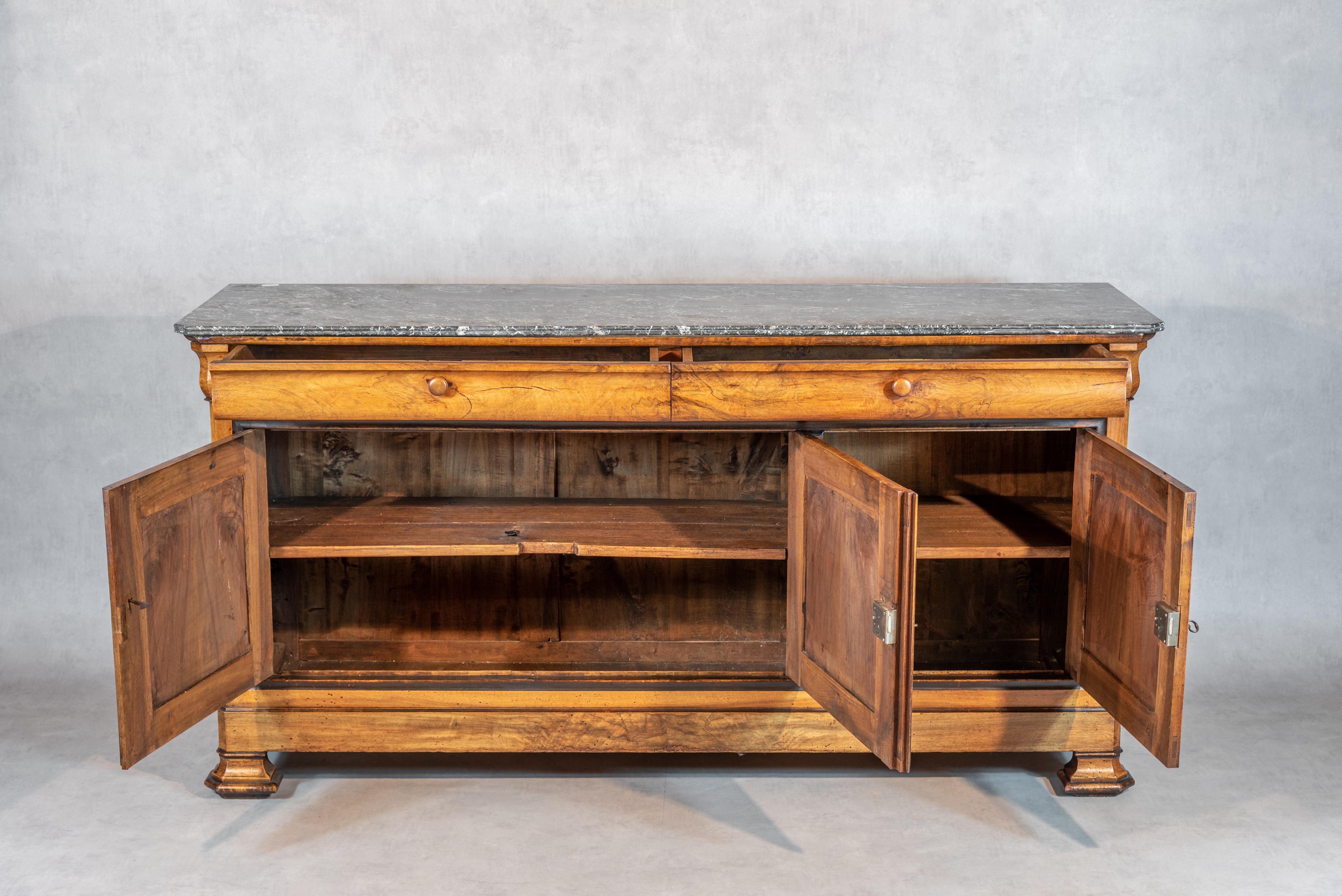 A superb French Louis Philippe Period Walnut Enfilade. This enfilade features three cabinet doors that give way to ample storage space inside, as well as two drawers on top. The front facades on the doors have a gorgeous walnut symmetrical veneer