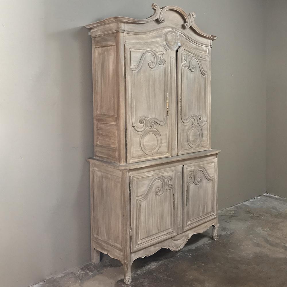 19th century French Louis Philippe Period whitewashed buffet a deux corps hails from the master artisans of Normandie, and was fashioned by hand from the local indigenous white oak. The trademark crown appears before the lavishly scrolled door