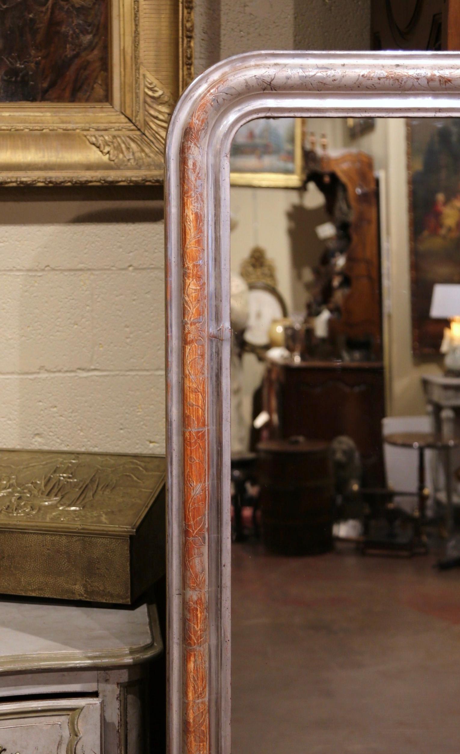 Crafted in the Burgundy region of France circa 1860, the 6 foot tall antique frame has traditional lines with rounded corners and is decorated with a discrete engraved floral decor. The large wall mirror is in excellent condition with the original