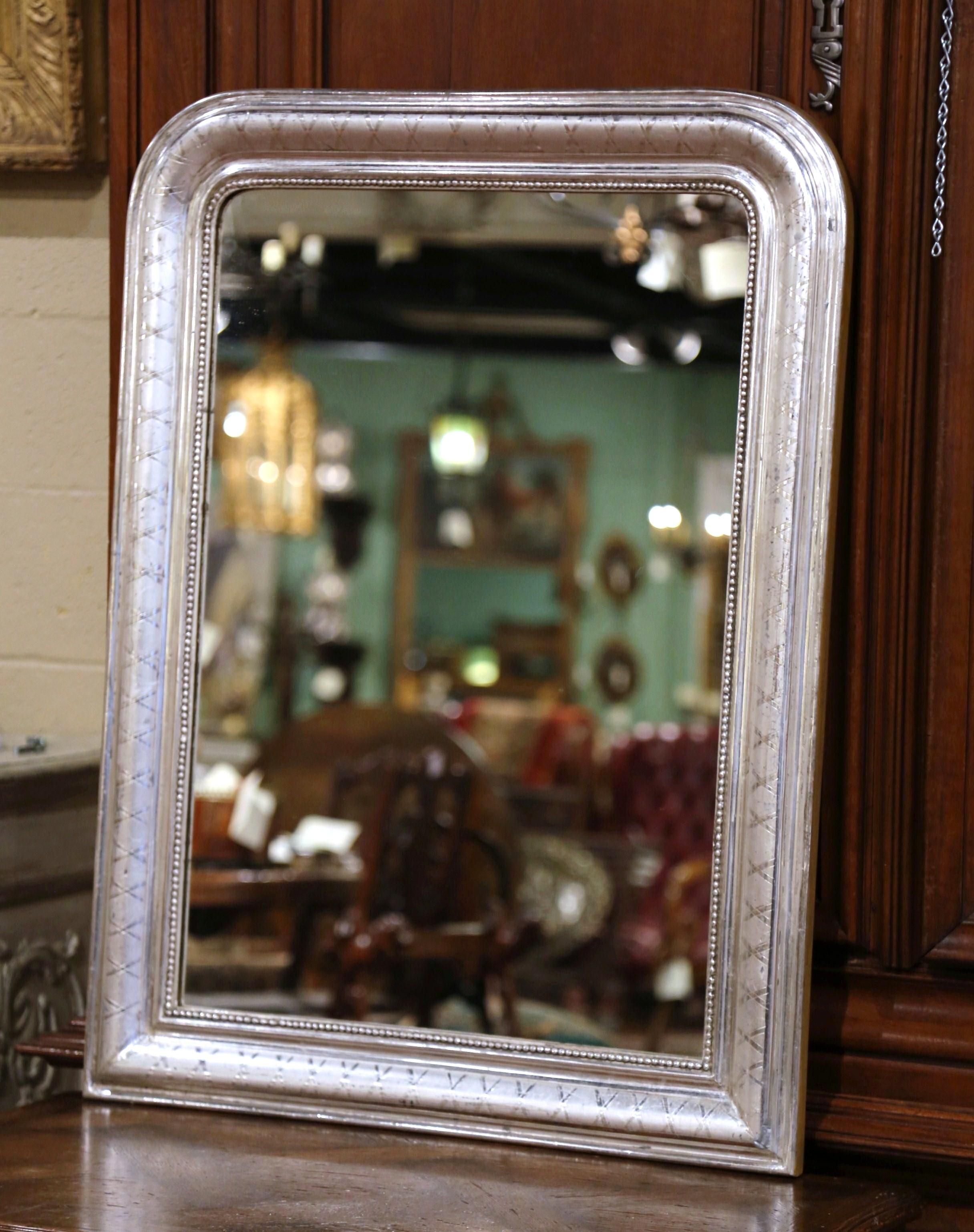 Crafted in the Burgundy region of France, circa 1870, the rectangular wall mirror has traditional, timeless lines with rounded corners. The frame is decorated with a luxurious silver leaf finish, further embellished with a discrete engraved X decor