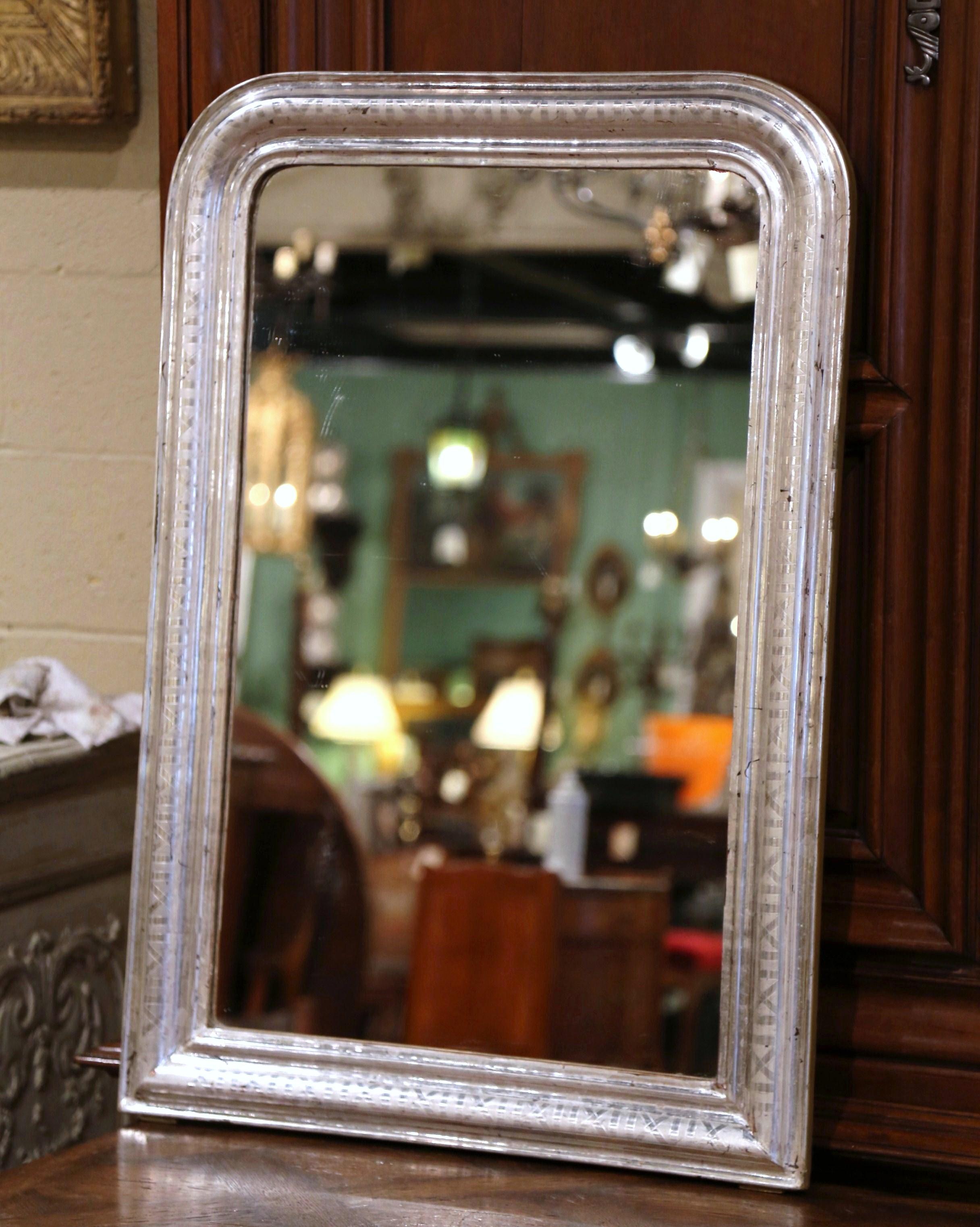 Crafted in the burgundy region of France, circa 1870, the rectangular wall mirror has traditional, timeless lines with rounded corners. The frame is decorated with a luxurious silver leaf finish, further embellished with an engraved geometric decor
