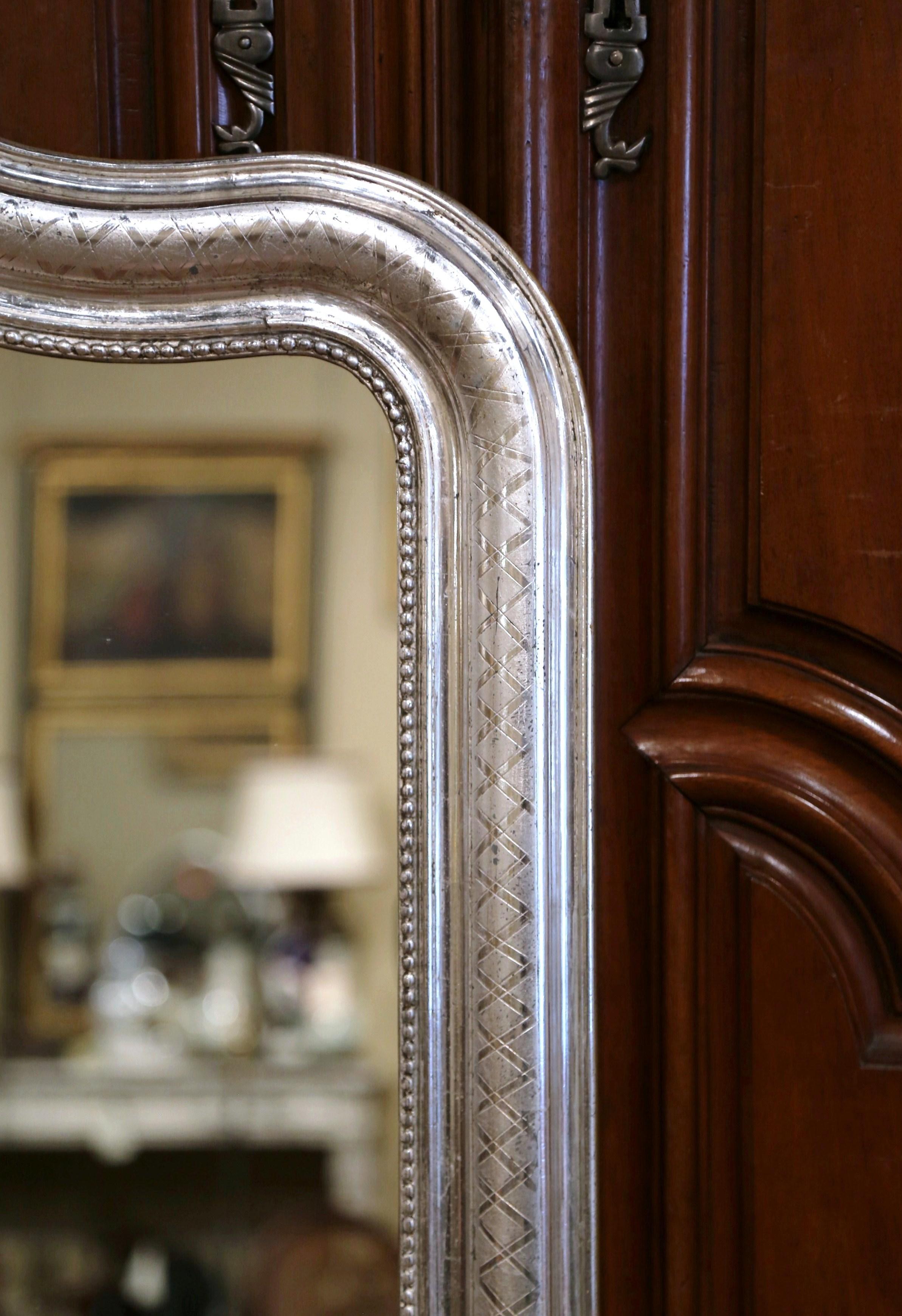 Crafted in the burgundy region of France, circa 1870, the antique wall mirror has traditional, timeless lines with rounded corners and embellished with an arched top. The elegant frame is decorated with a luxurious silver leaf finish, with an