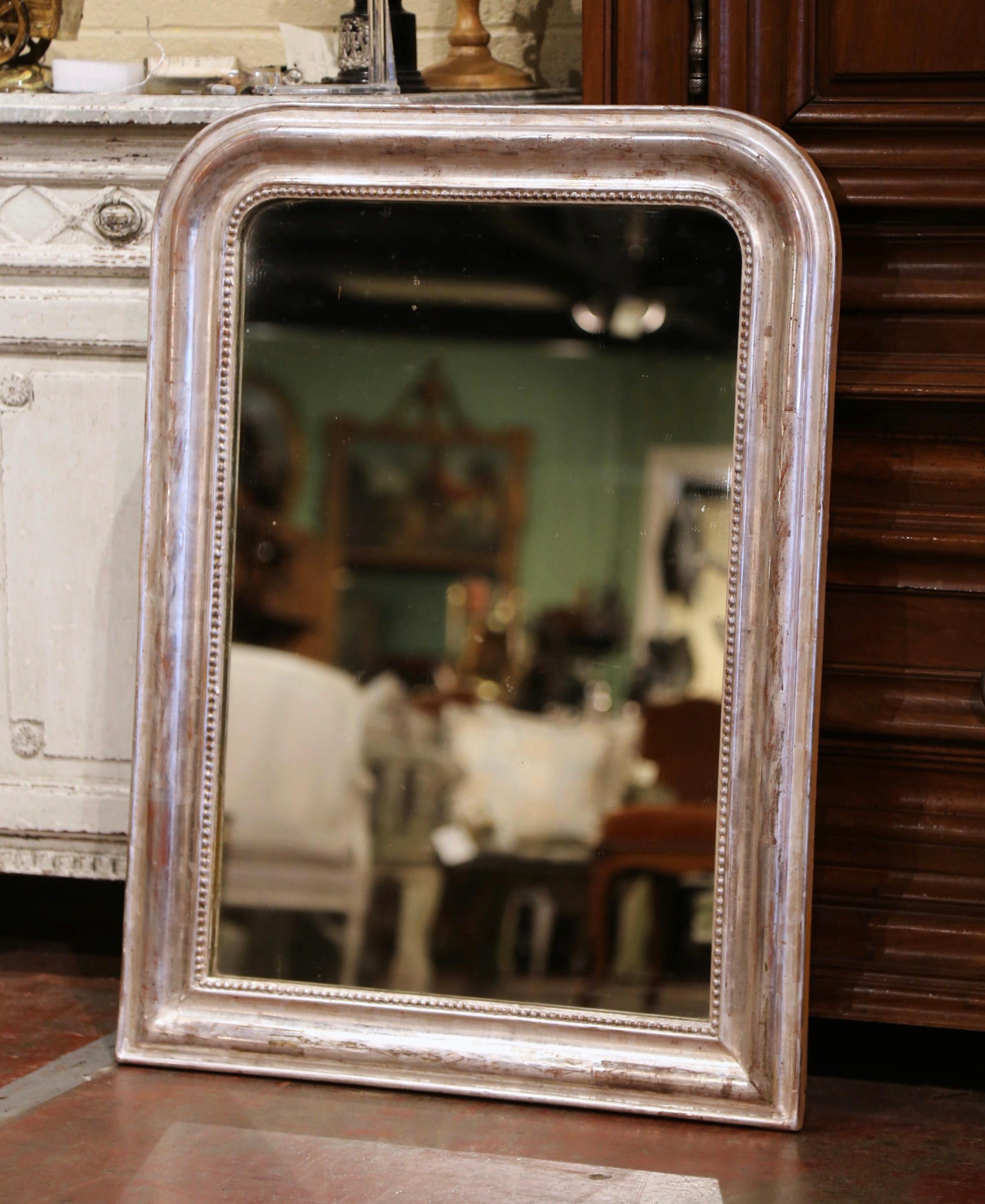Crafted in the Burgundy region of France, circa 1870, the rectangular wall mirror has traditional, timeless lines with rounded corners. The frame is decorated with a luxurious silver leaf finish, further embellished with carved bead decor around the