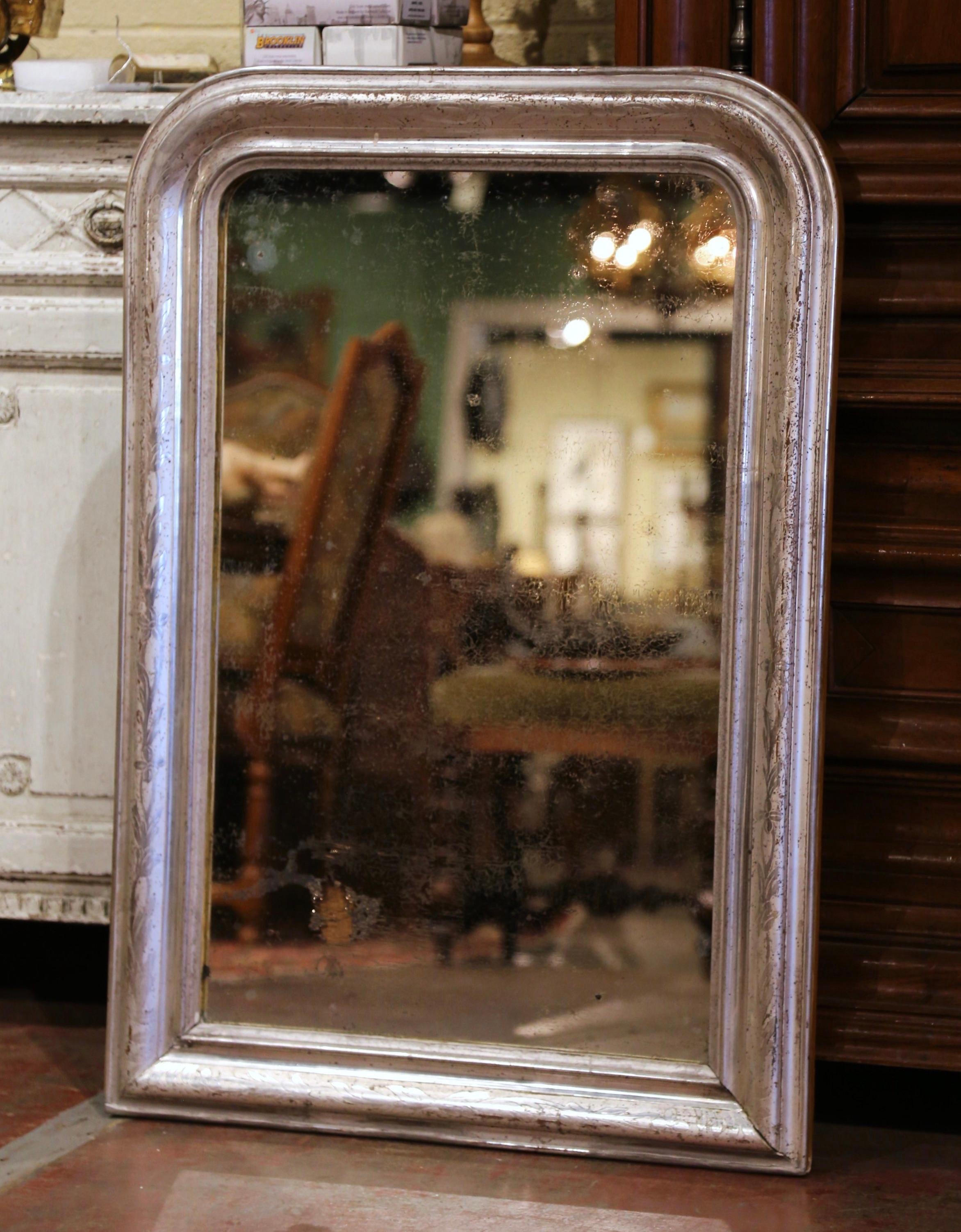 Crafted in the Burgundy region of France, circa 1870, the rectangular wall mirror has traditional, timeless lines with rounded corners. The frame is decorated with a luxurious silver leaf finish, further embellished with discrete engraved decor