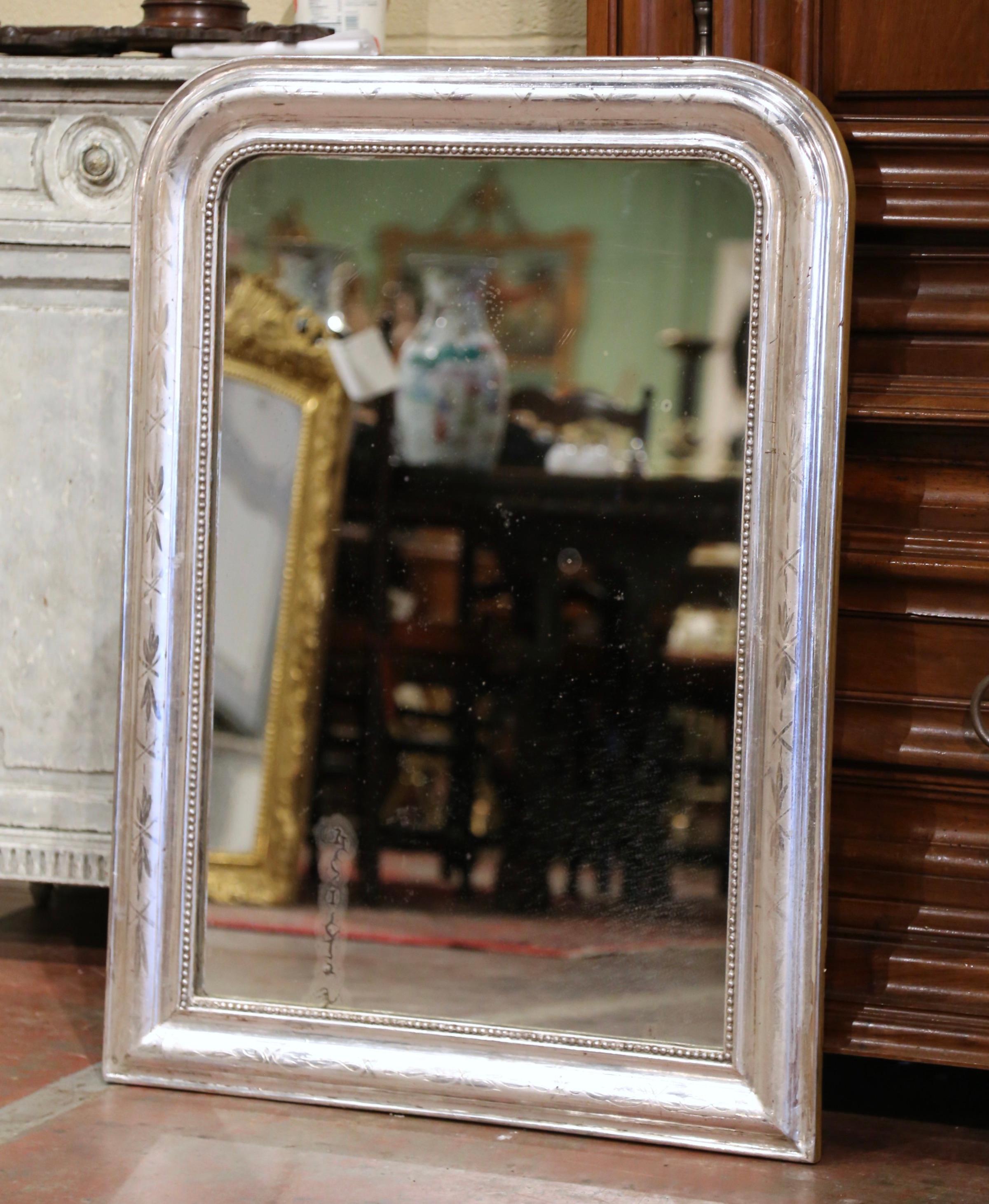 Crafted in the Burgundy region of France, circa 1870, the elegant antique mirror has traditional, timeless lines with rounded corners. The rectangular frame is decorated with a luxurious silver leaf finish over discrete engraved floral and geometric