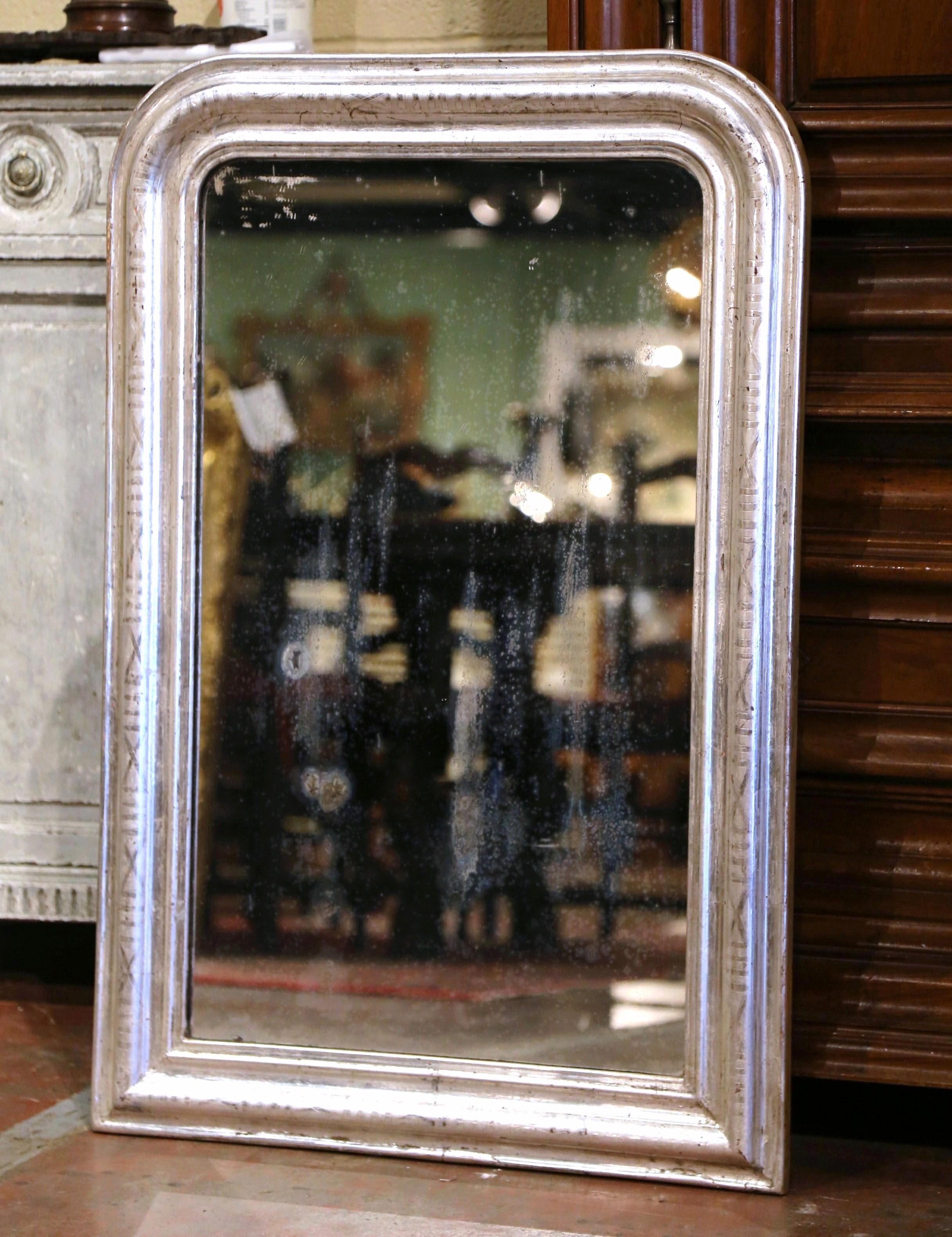 Crafted in the Burgundy region of France, circa 1870, the rectangular antique mirror has traditional, timeless lines with rounded corners. The frame is decorated with a luxurious silver leaf finish over discrete engraved geometric motifs. The