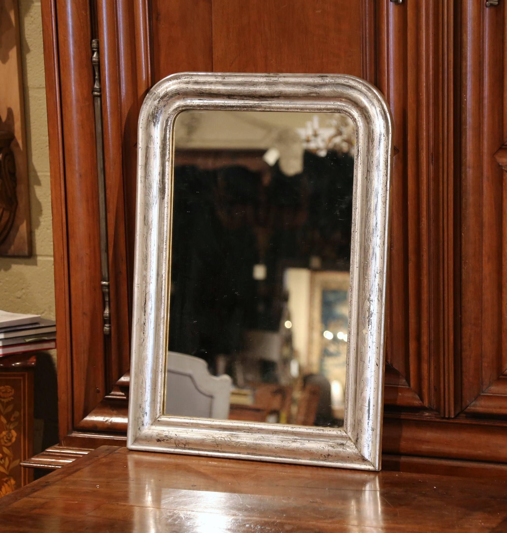 This elegant, antique mirror was crafted in France, circa 1860. Rectangular in shape, the small wall hanging mirror features discrete engraved floral motifs around the decorative, silver leaf frame. The traditional, Louis Philippe style piece is in