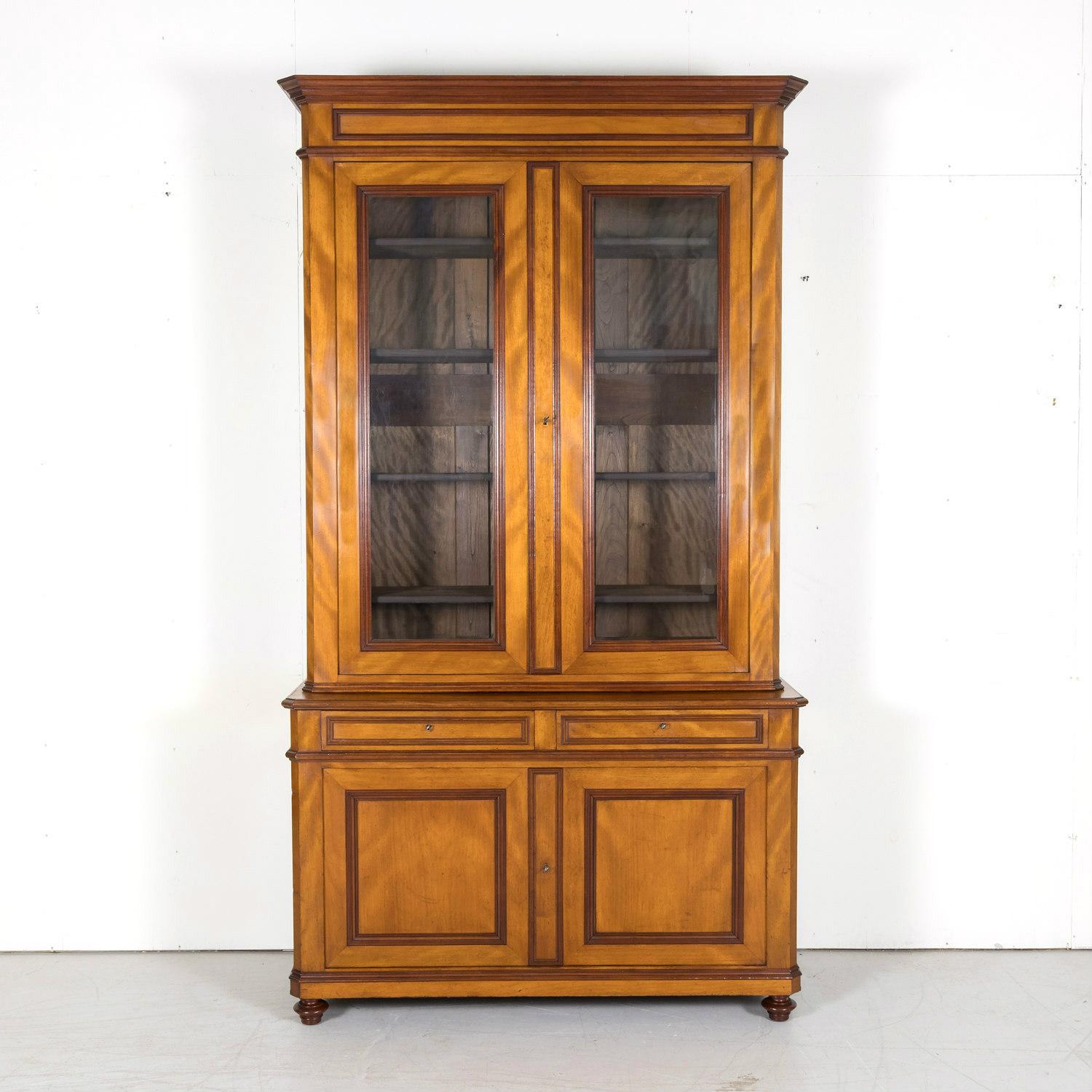 A handsome 19th century French Louis Philippe style bibliothèque or bookcase handcrafted of flame mahogany by talented artisans near Lyon, circa 1880s. The upper bookcase has a moulded cornice with canted corners above a pair of three-quarter glass