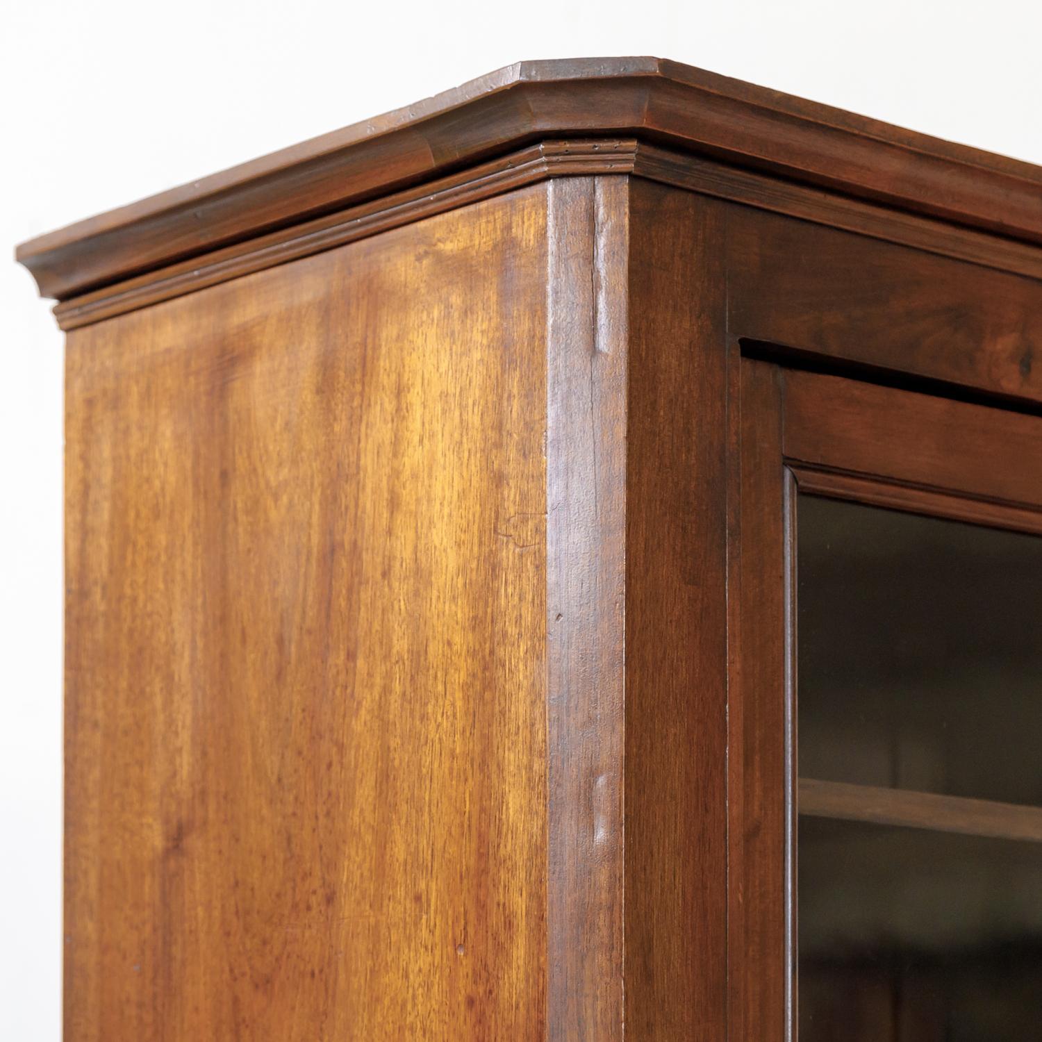 19th century French Louis Philippe style bibliothèque or bookcase handcrafted of solid walnut by talented artisans near Honfleur, a commune in the Calvados department in northwestern France, circa 1870s. Having a molded cornice with canted corners