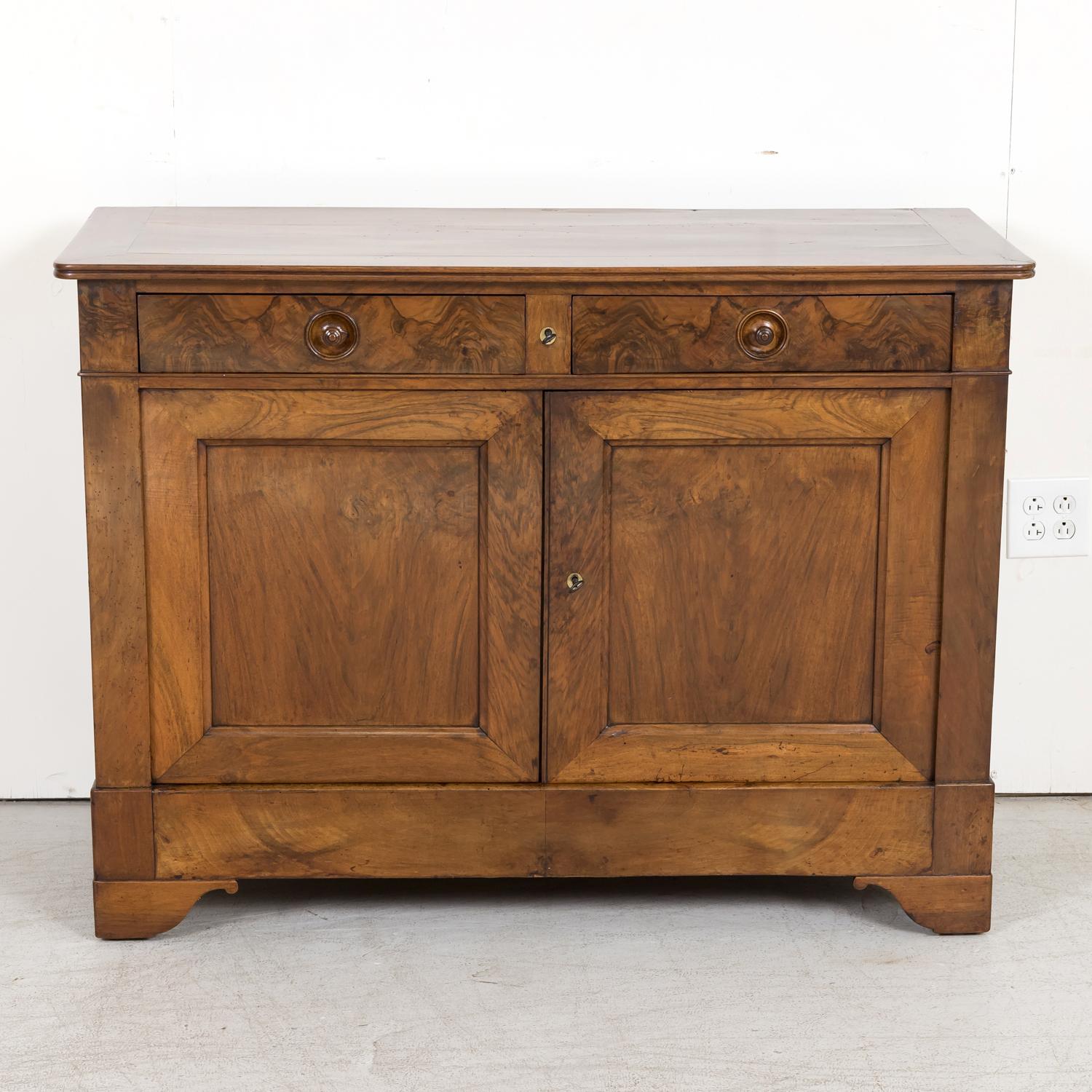 A handsome 19th century French Louis Philippe style buffet handcrafted of walnut with a bookmatched walnut front near Carcassonne, a fortified city in the department of Aude, in the region of Occitanie, circa 1880s, having a banded plank top with