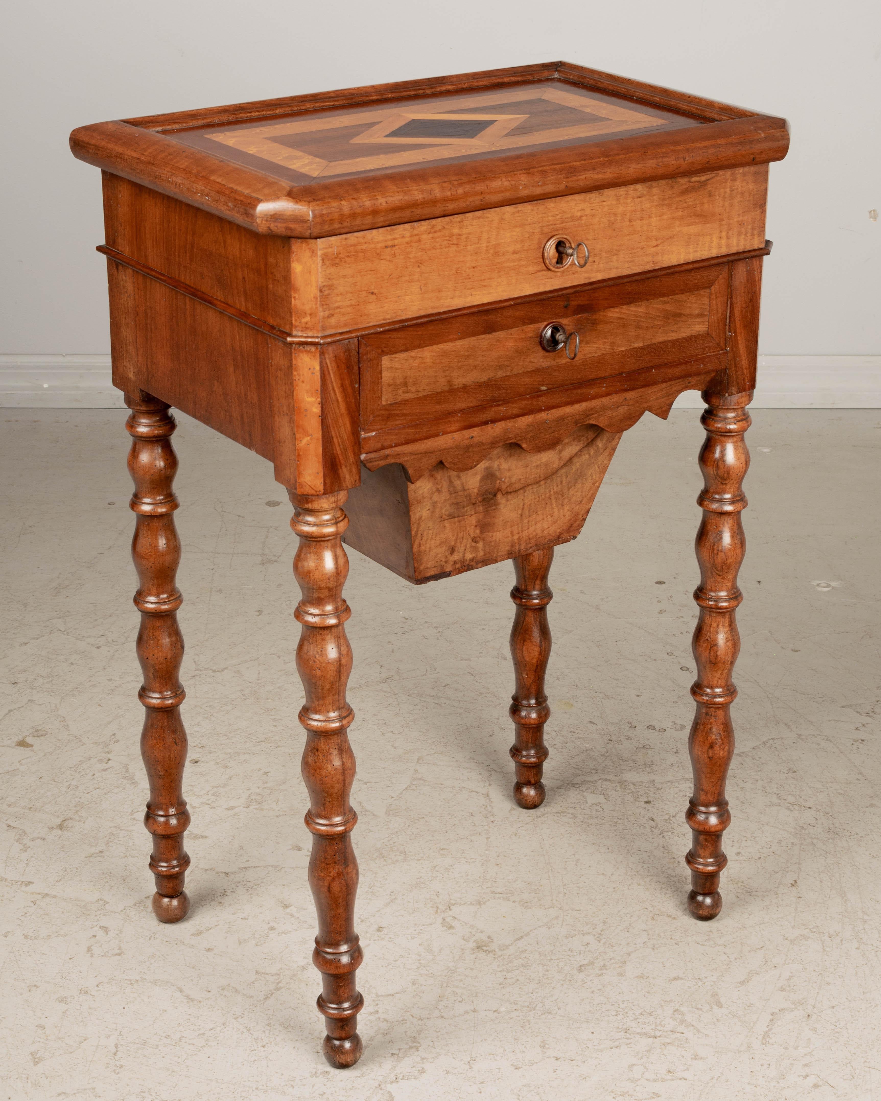 A fine early 19th century French Louis Philippe travailleuse, or work table used for storing sewing implements and embroidery silk. Made of walnut with two dovetailed drawers, each with working lock and key and a deep pull-out compartment below.