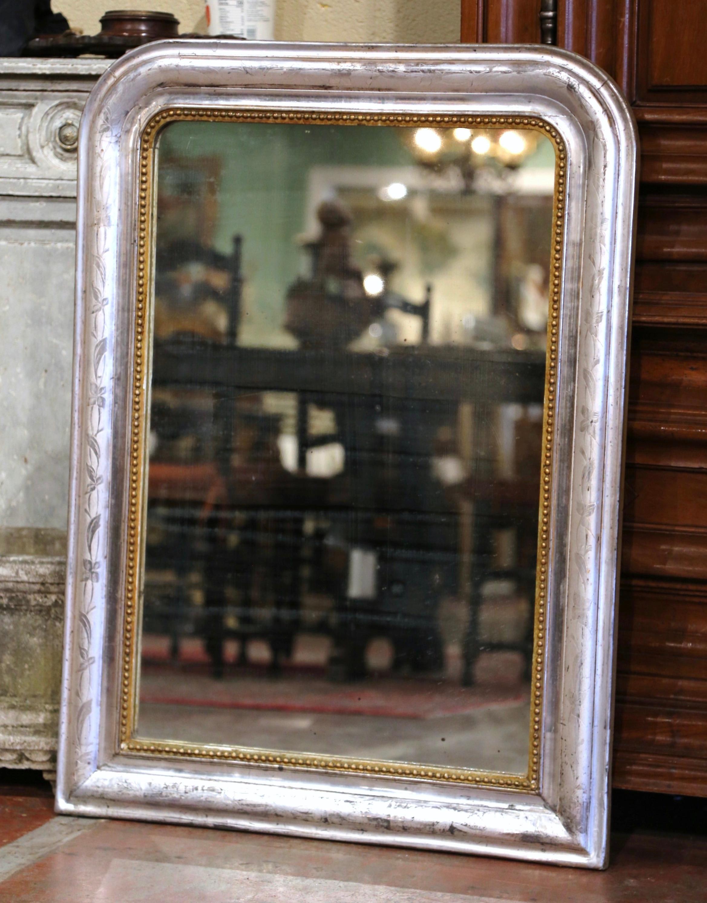 Crafted in the Burgundy region of France, circa 1870, the rectangular antique mirror has traditional, timeless lines with rounded corners. The frame is decorated with a luxurious silver leaf finish over discrete engraved floral motifs, and further