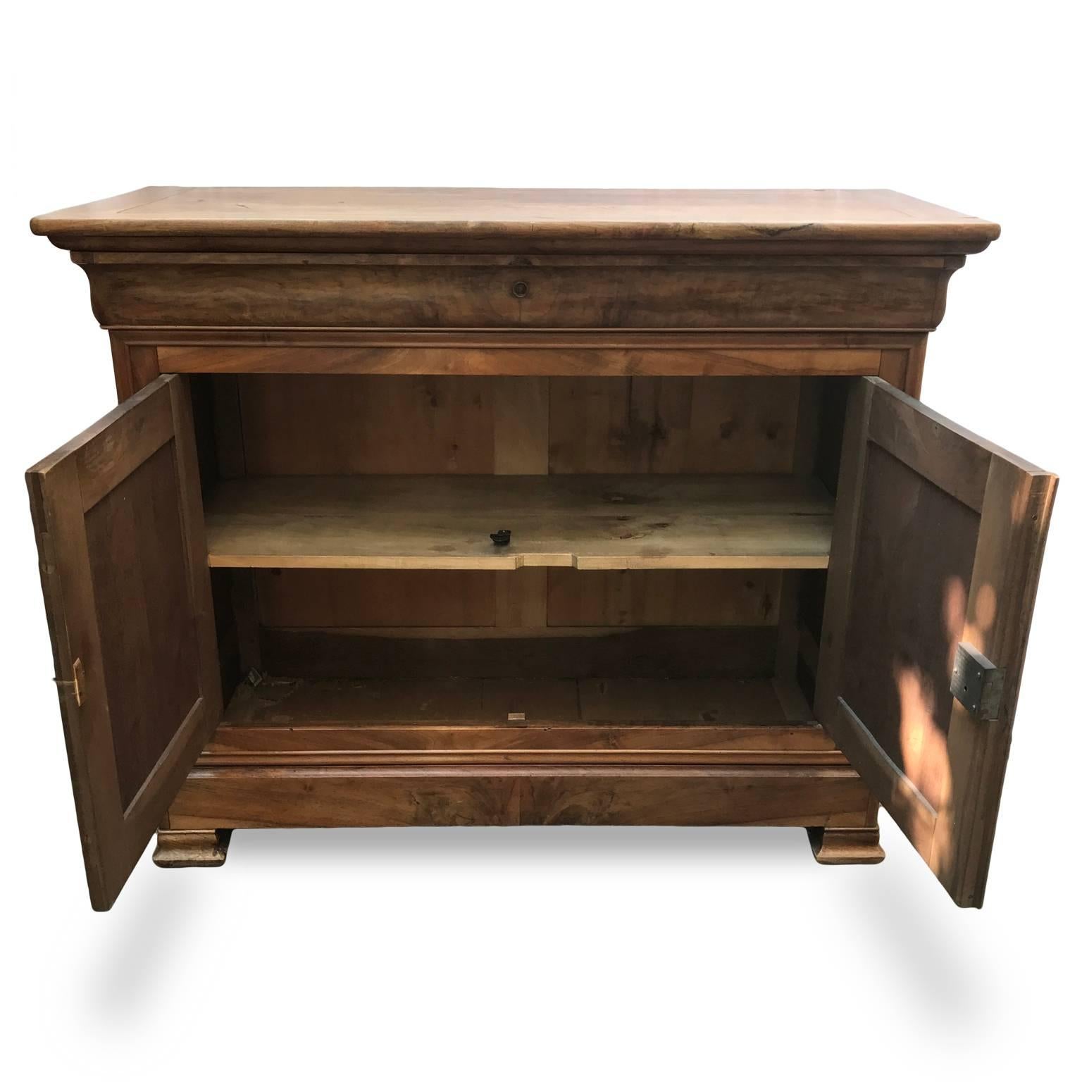 This stunning flame walnut two-door sideboard dates back to circa 1870, it is a French antique buffet coming from a private residence in Milan and it is in good age related condition with a beautiful glow and patina.
It features one large drawer