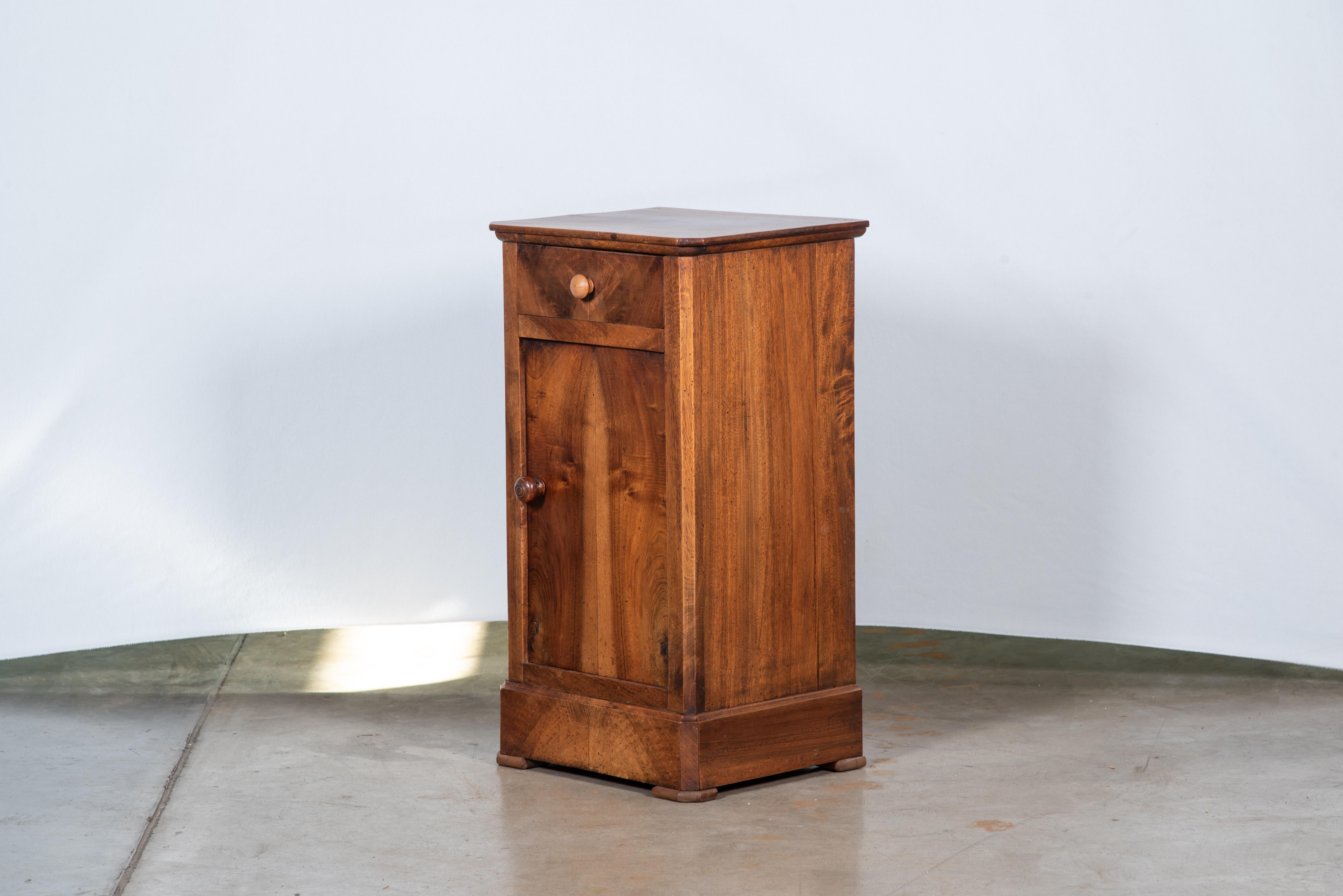 Step into the elegance of the 19th Century French Louis Philippe Walnut Veneer Nightstand, a piece that epitomizes the sophistication of its era. Crafted with meticulous attention to detail, this nightstand boasts the timeless allure of walnut