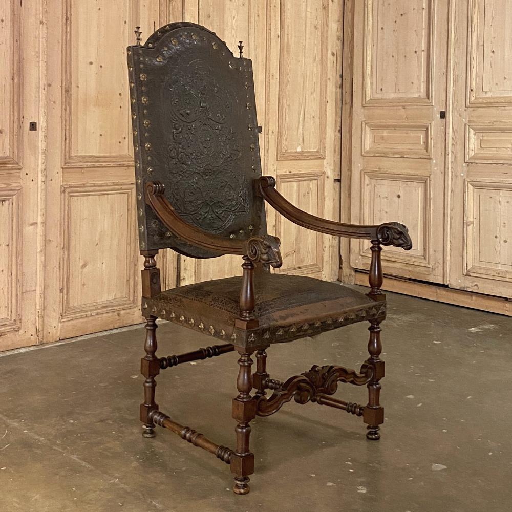 19th century French Louis XIII armchair with embossed leather was sculpted from fine French walnut, and features a majestic presence enhanced by the boldly carved rams' heads at the tip of each gracefully scrolled armrest. Atop the arched seatback