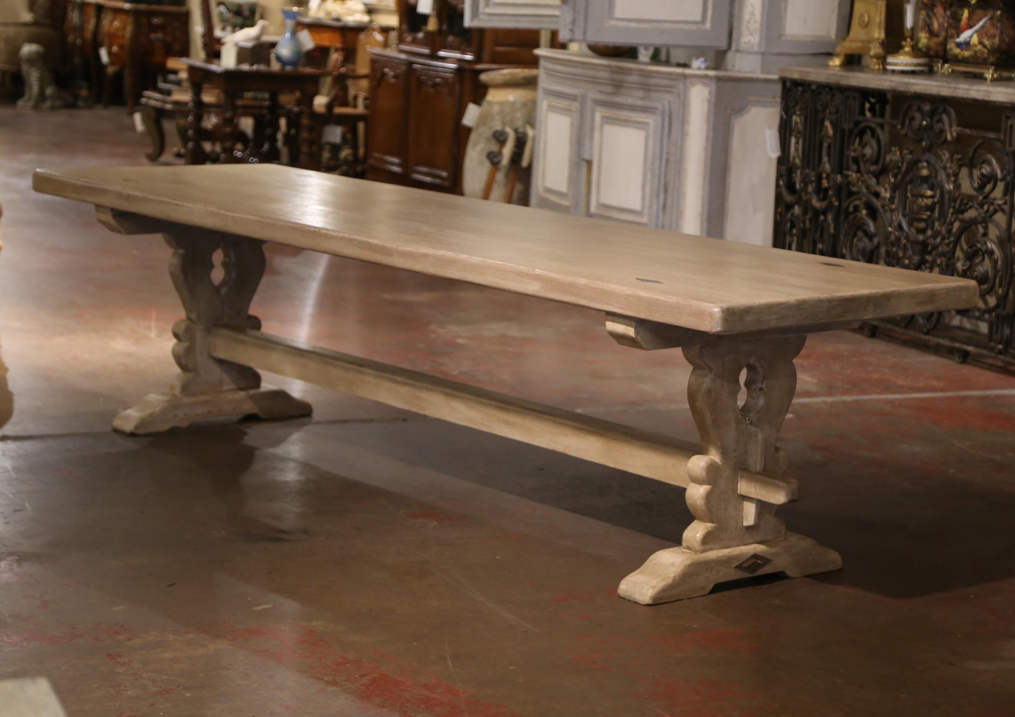 This elegant antique refectory table was crafted in Normandy, France circa 1870. Built of solid oak, and almost 10 feet in length, the table stands on carved trestle support legs ending with molded shoe feet, and joined together with a cross bottom