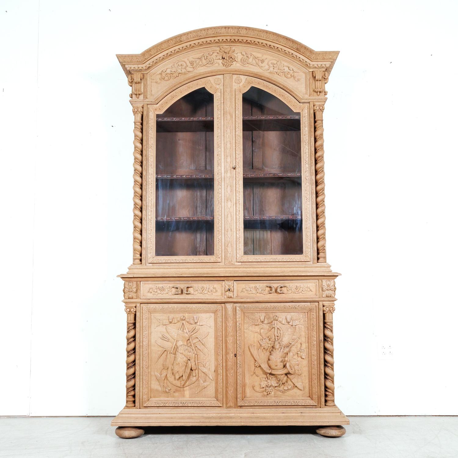 A handsome mid-19th century French Louis XIII style carved hunting buffet deux corps or bibliothèque de chasse, circa 1850s, handcrafted in Lyon of solid oak that has been bleached, allowing the carved motifs of the antique cabinet to gain