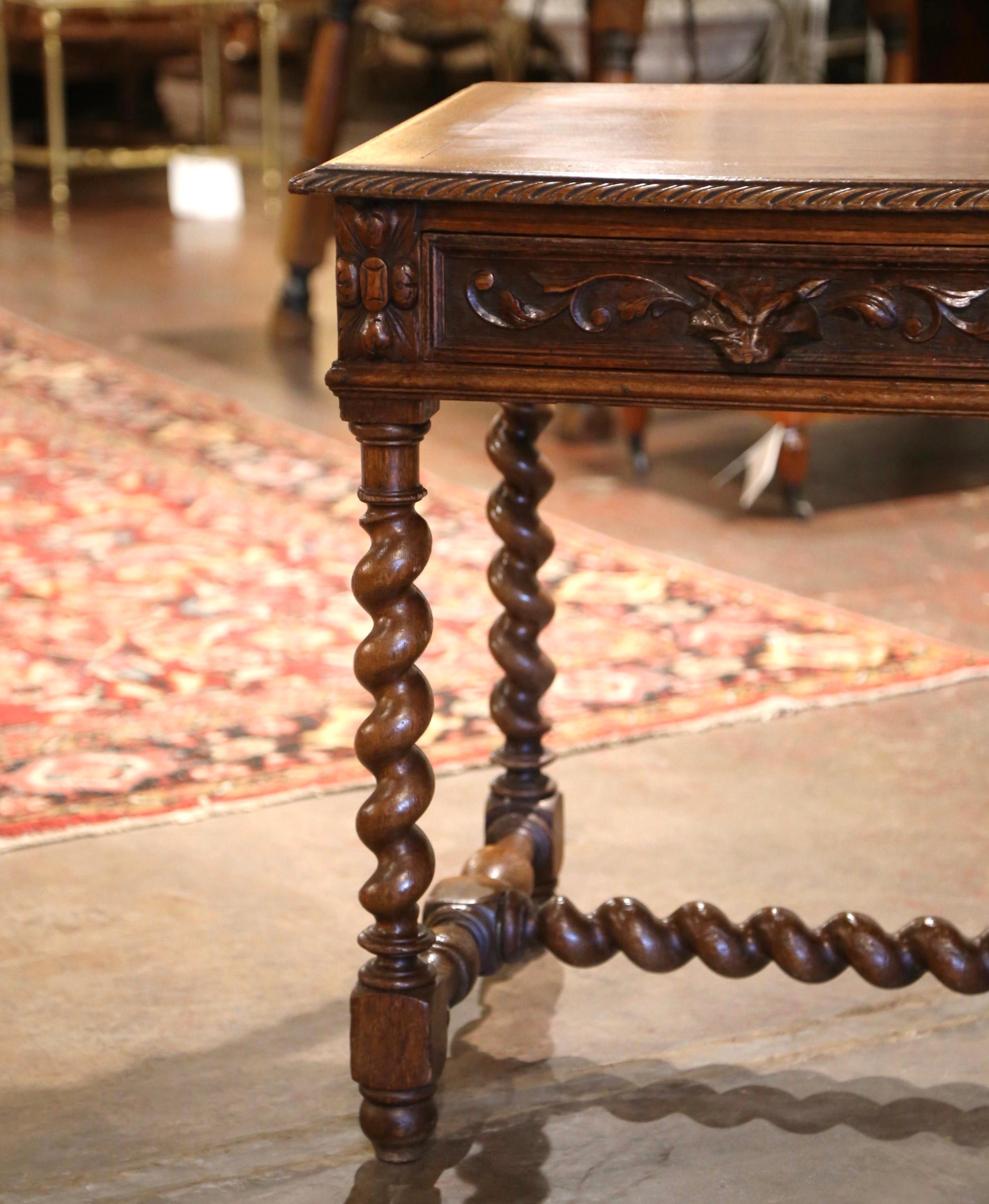 Crafted in Northern France, circa 1870, the antique writing table stands on thick carved barley twist legs ending with turned feet, and connected with an elegant stretcher at the base. The table is fitted with two drawers across the front decorated