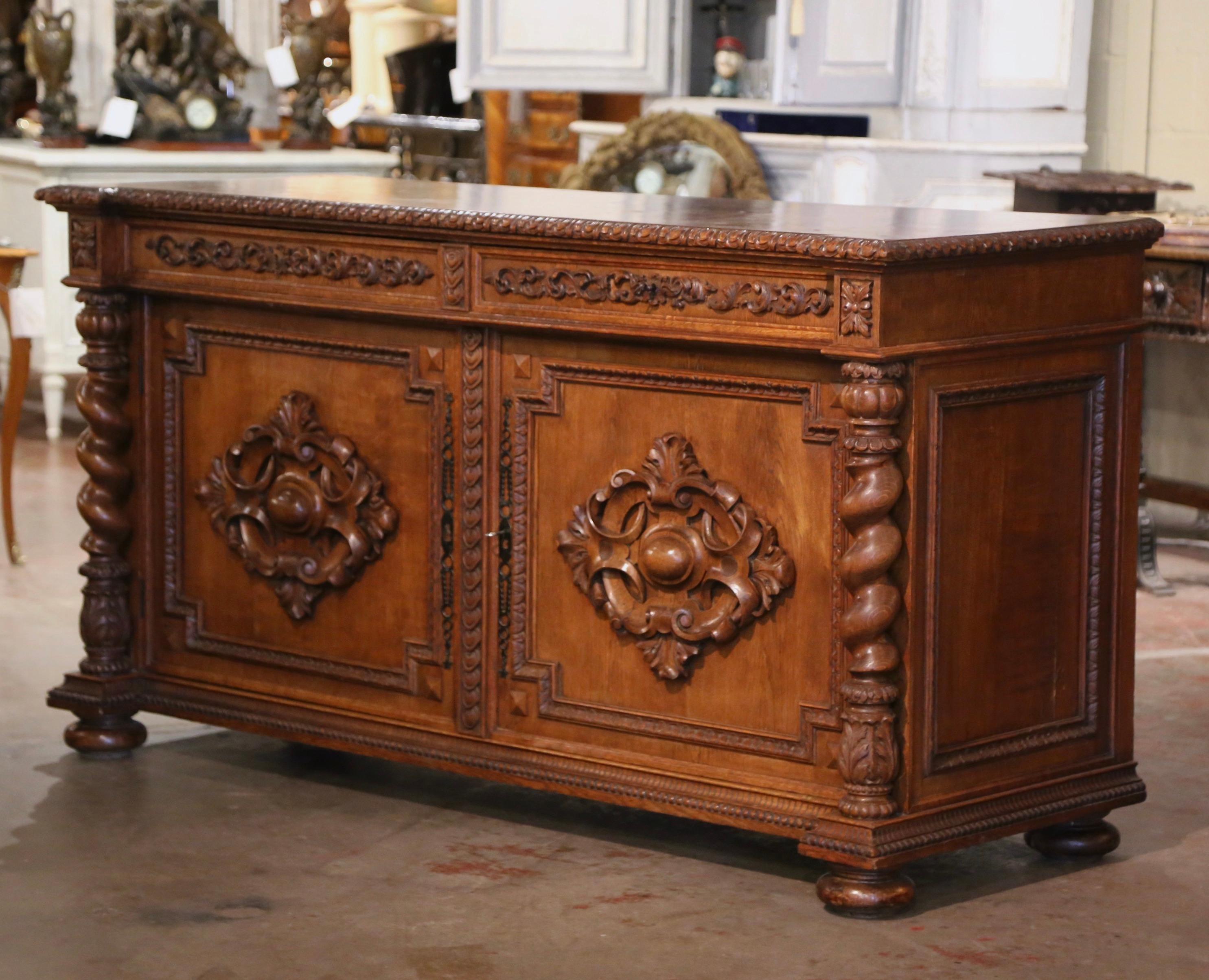 This elegant antique buffet was crafted in southwest France, circa 1850. Built of oak, the cabinet stands on front bun feet over a intricately carved bottom plinth. The cabinet features a pair of doors decorated with high relief crest motifs on