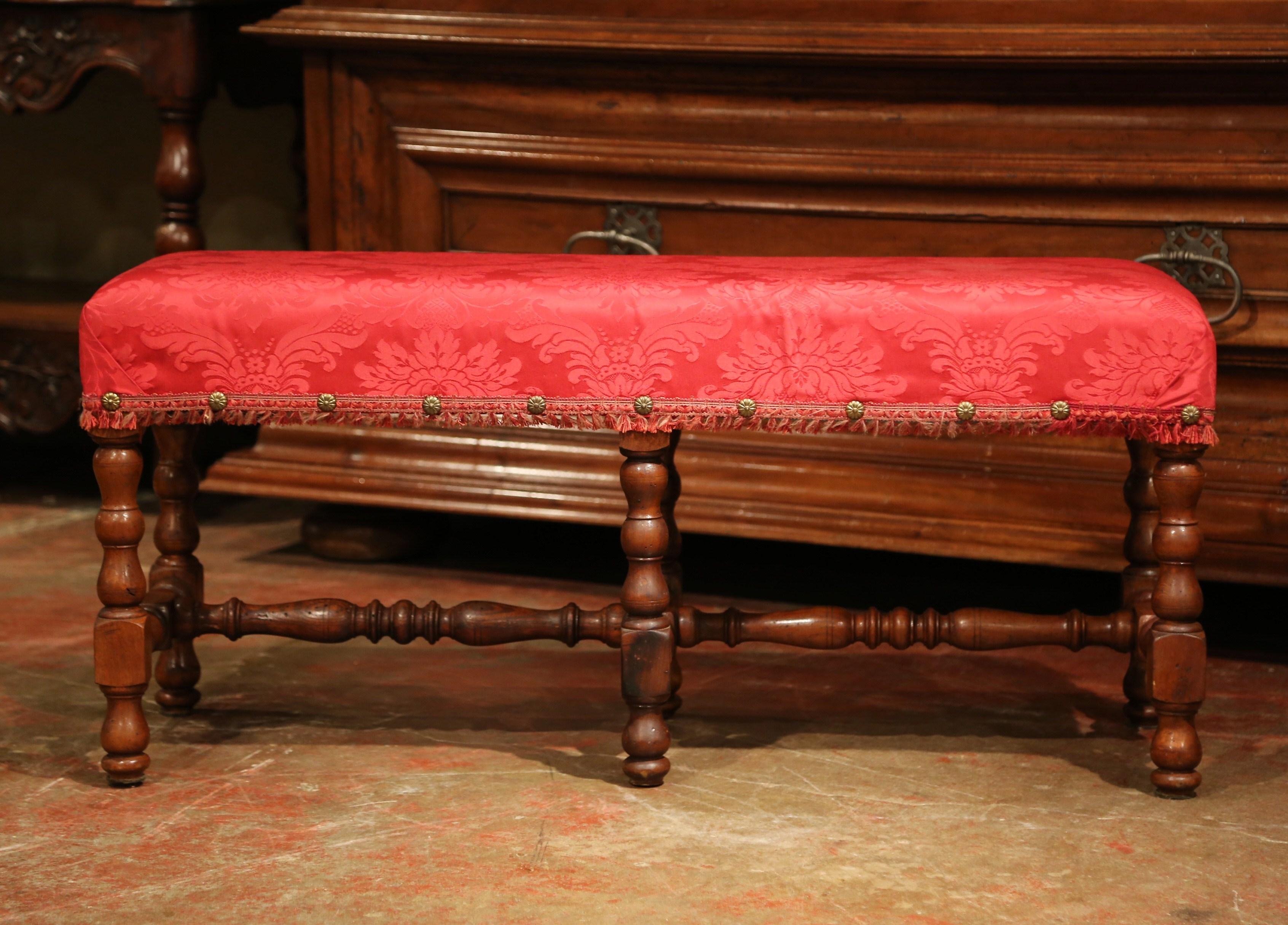 Add extra seating to a hallway, formal living room, or the foot of a queen sized bed with this elegant, antique bench. Crafted in France circa 1860, this fruit wood piece features four delicately carved, turned legs with a matching stretcher. The