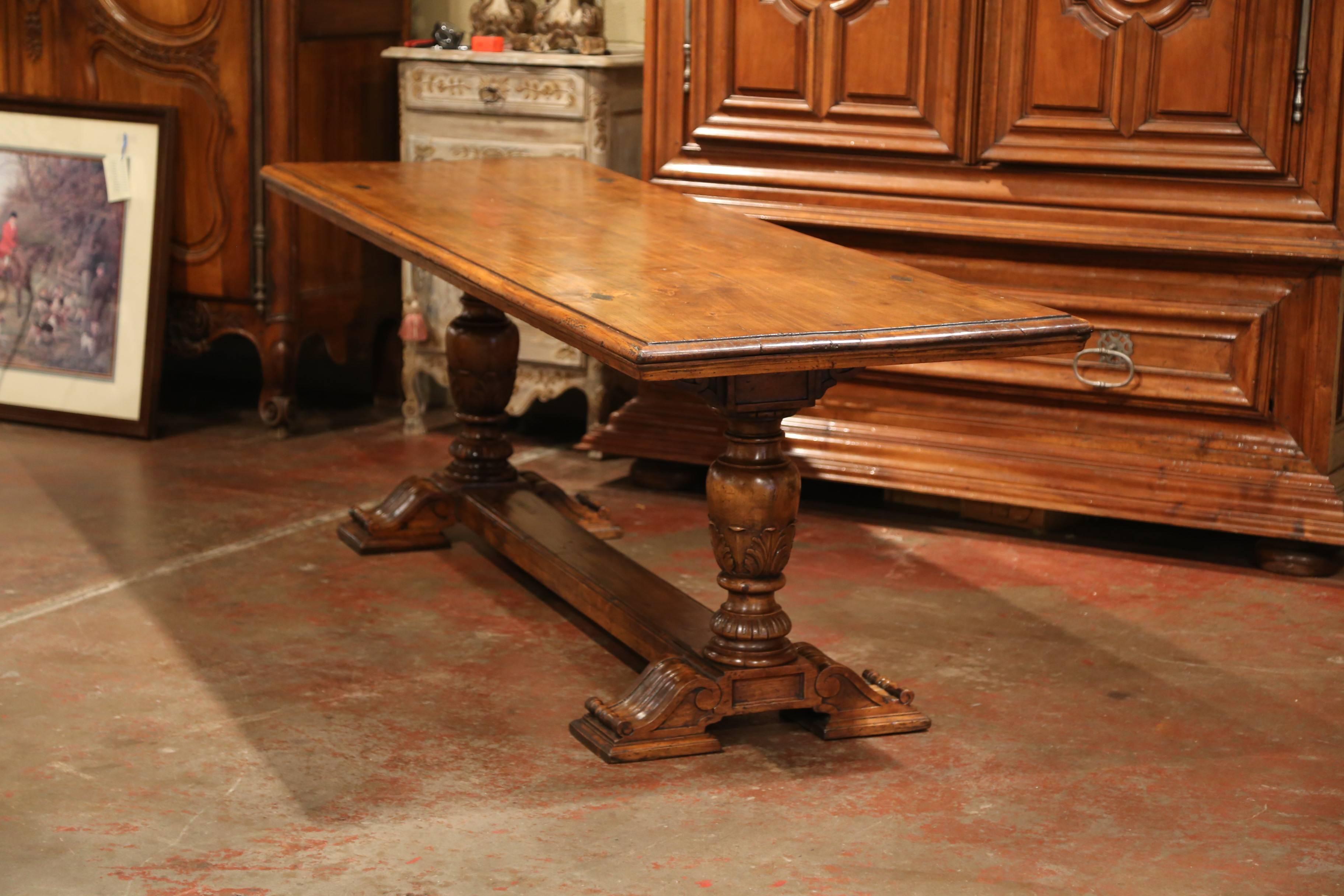 This large fruitwood dining room table was crafted in the Perigord region of France, circa 1860. The long table features a solid plank top with four decorative diamond shape iron nails in each corner. The farm table has two hand-carved pedestal legs