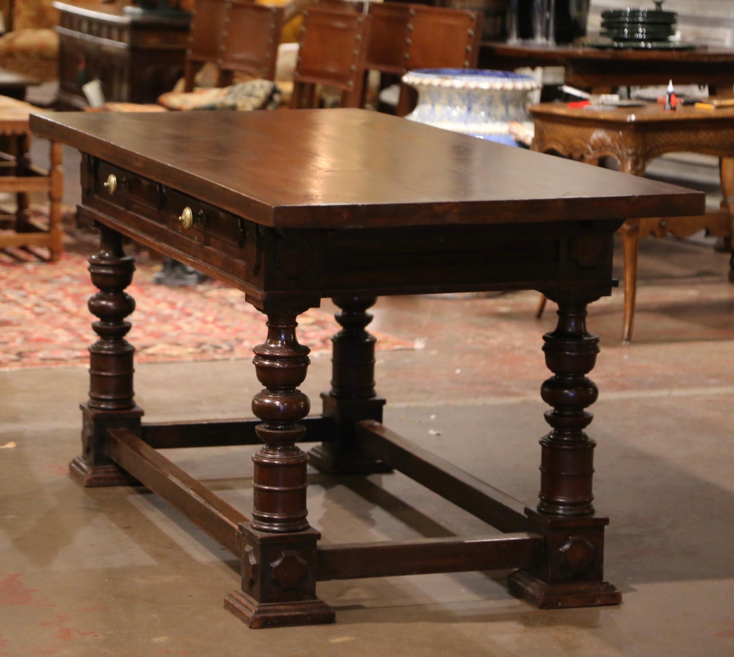 Crafted in the Perigord region of France, circa 1860, the antique writing table stands on thick carved turned legs ending with square feet, and embellished with an elegant rectangular box stretcher at the base. The large table features two paneled